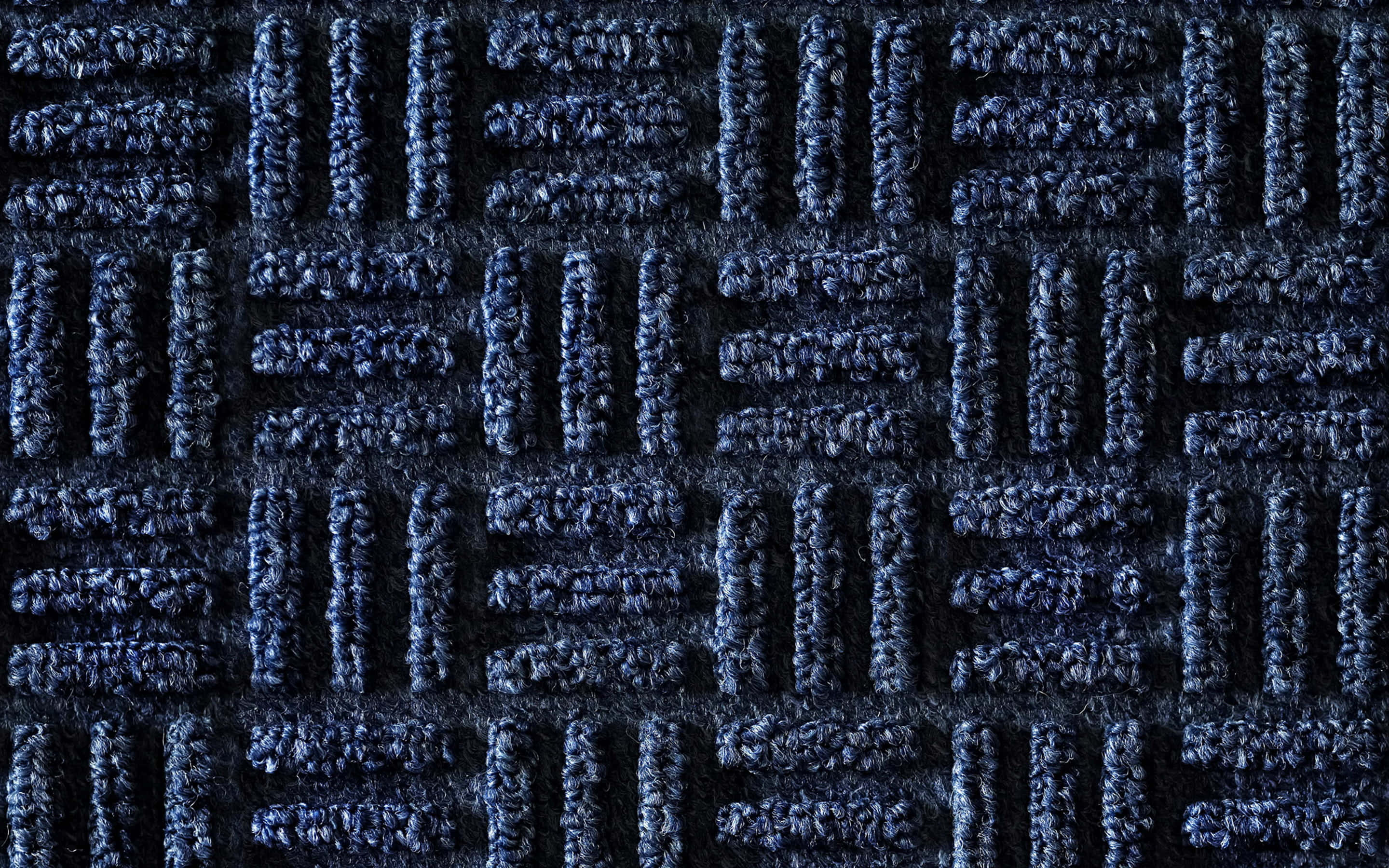 Carpet 桌布 壁紙 — 深藍色紋理地毯的特寫，帶有重複的垂直和水平編織圖案。
