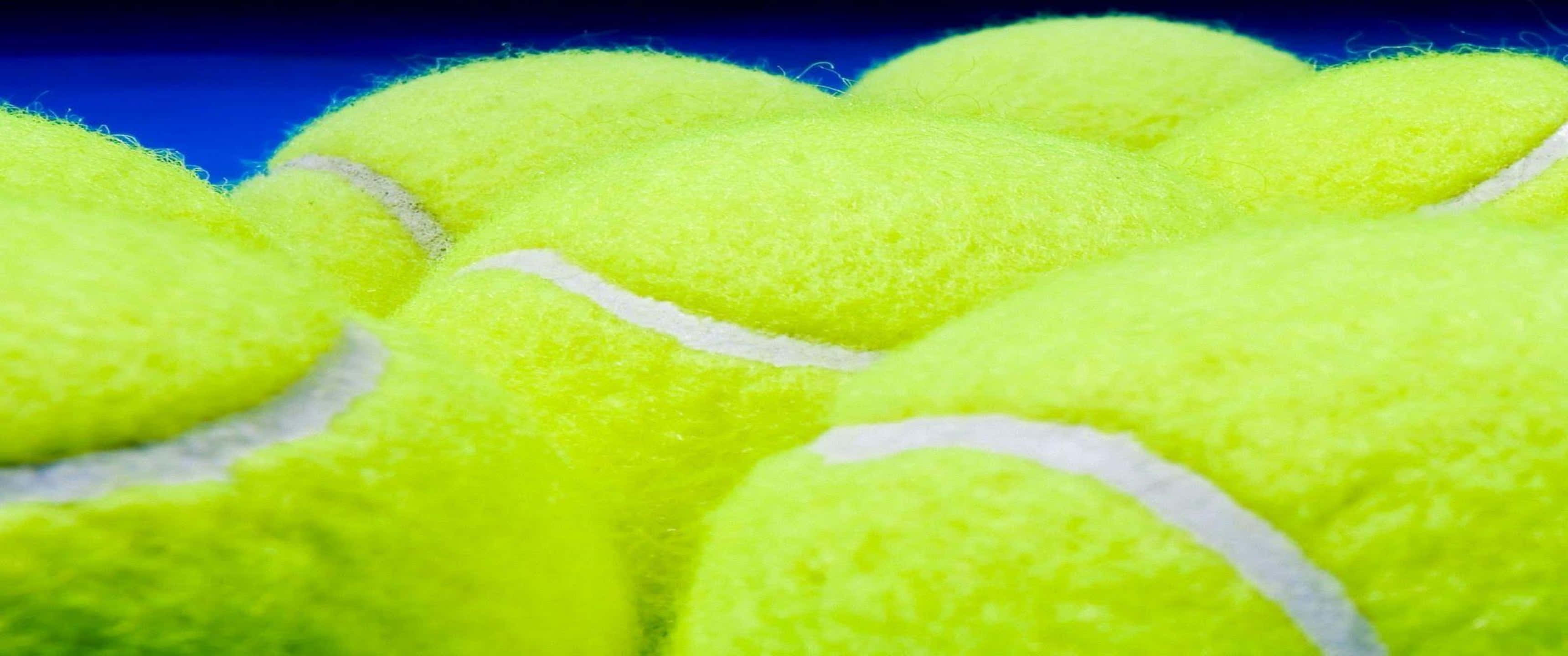 3440x1440p Tennis 桌布 壁紙 — 深藍色背景上，帶有白色縫線的亮黃色網球特寫。