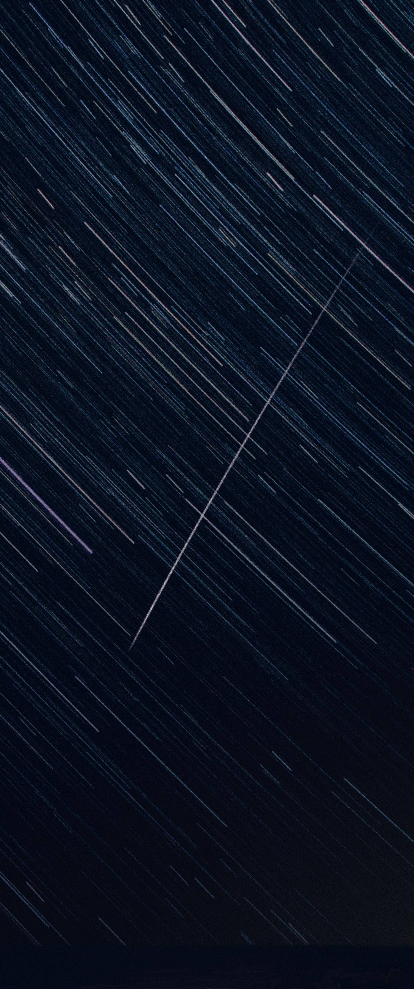 直式 桌布 壁紙 — 深藍色背景上，長曝光攝影產生的對角線光條的星空夜空。