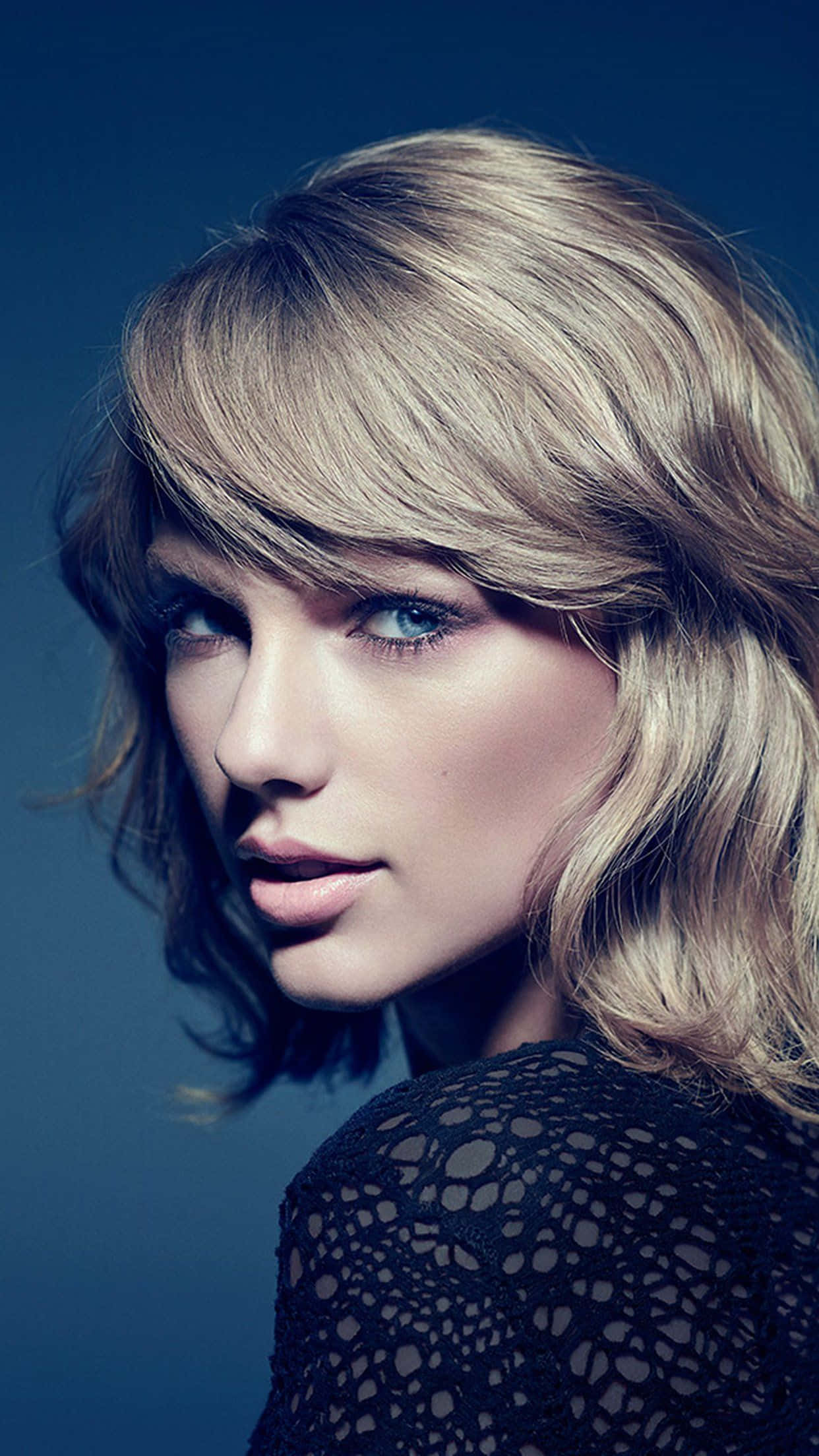 Taylor Swift iPhone 桌布 壁紙 — 深藍色背景下，一位金髮藍眼女性的特寫肖像。