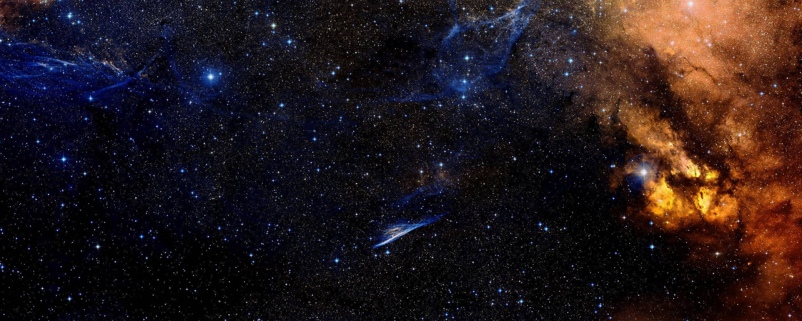 Dual 桌布 壁紙 — 深邃太空的宇宙景觀，充滿發光的橙色和藍色星雲以及無數閃爍的星星。