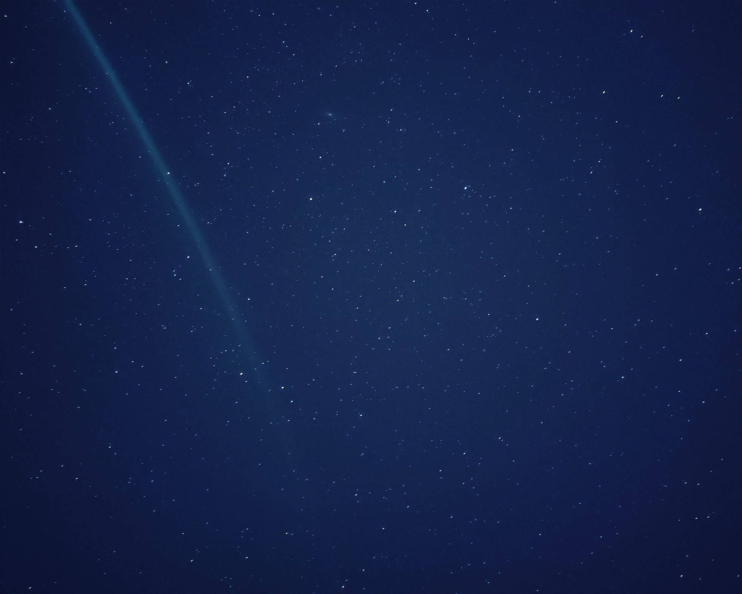 Velvet 桌布 壁紙 — 深邃的藍色夜空，佈滿無數星星，一條明亮的對角線彗尾劃過天際。