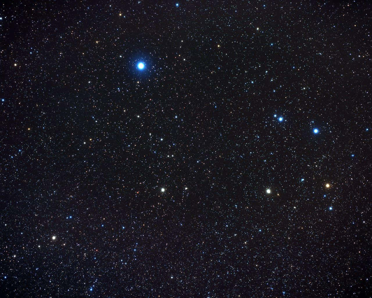Constellation 桌布 壁紙 — 深邃的黑色天空佈滿無數閃爍的星星，包括一顆突出的明亮藍色星星。