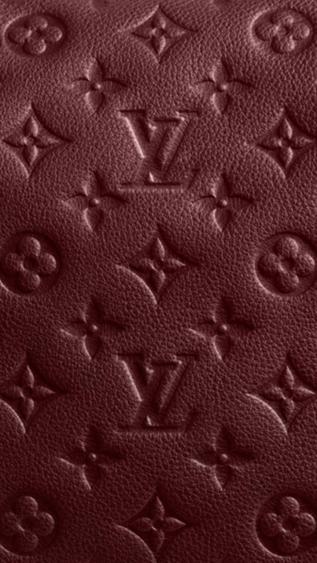 Louis Vuitton Pattern 桌布 壁紙 — 深酒紅色皮革特寫，帶有壓印路易威登字母組合圖案和紋理顆粒。