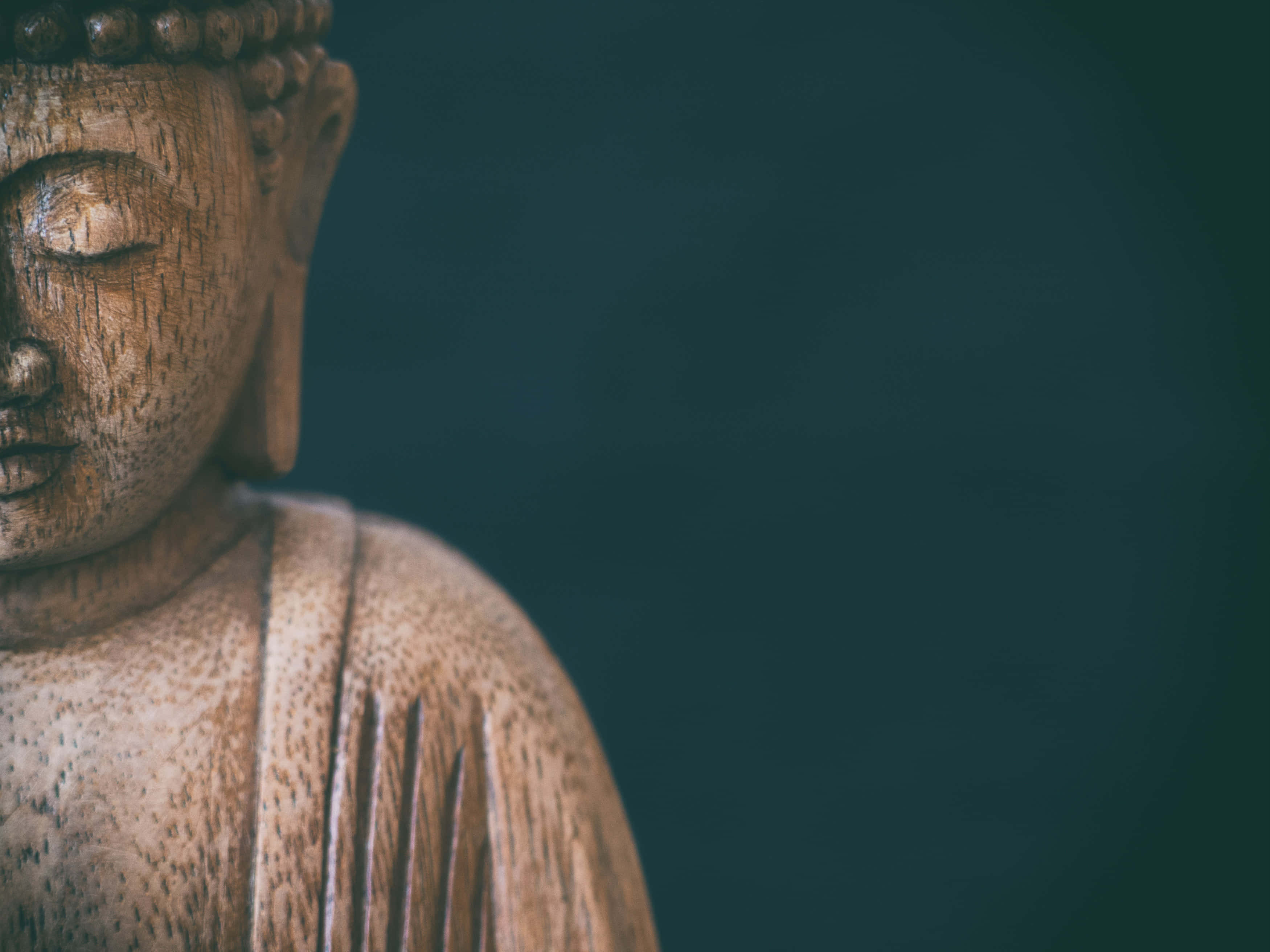 禪 桌布 壁紙 — 深青色背景上，閉著眼睛的寧靜木製佛像特寫。