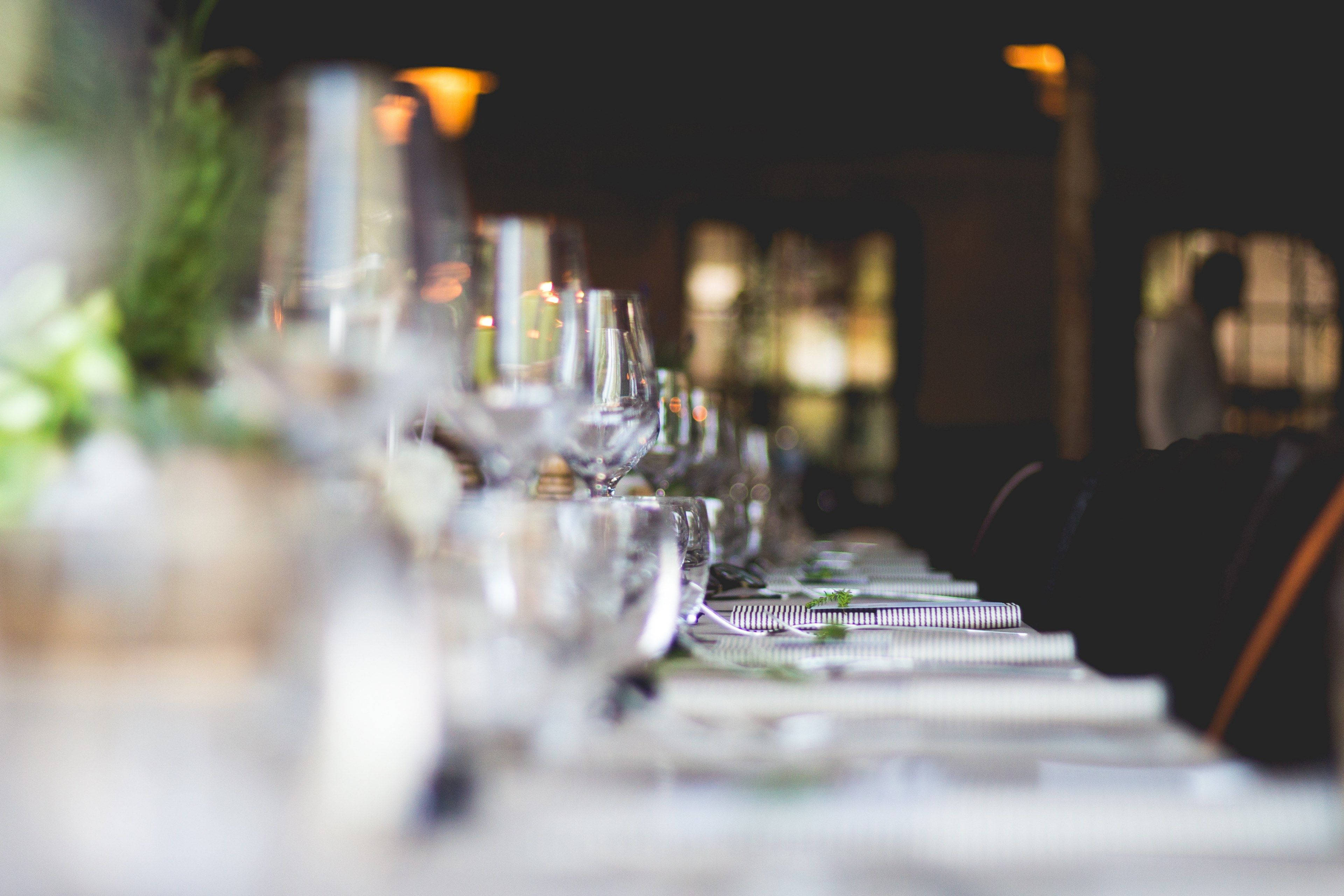 table 桌布 壁紙 — 淺景深捕捉了一張長長的優雅餐桌，擺放著酒杯和條紋餐巾，在溫暖的環境燈光下。