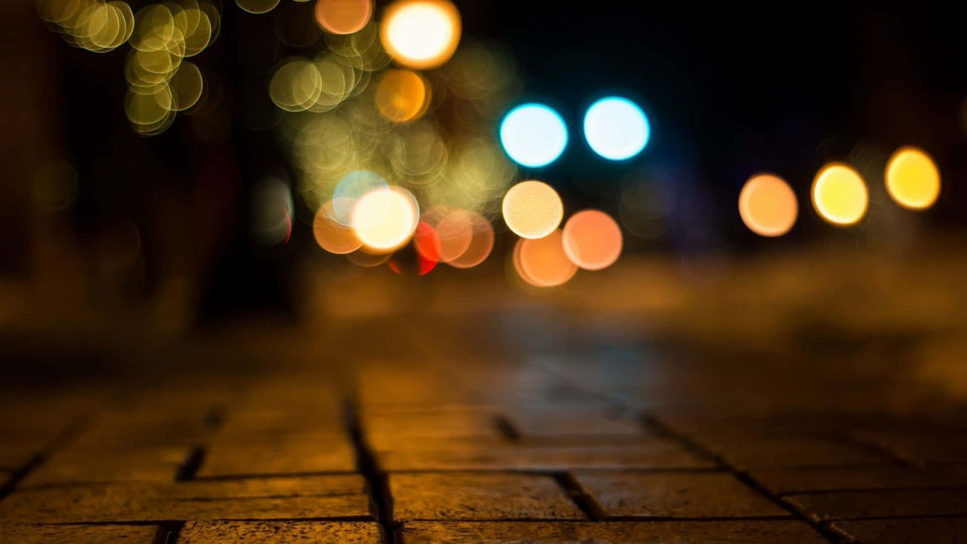 lighting 桌布 壁紙 — 淺景深捕捉夜晚鵝卵石路面上街燈和汽車發出的溫暖發光散景燈光。