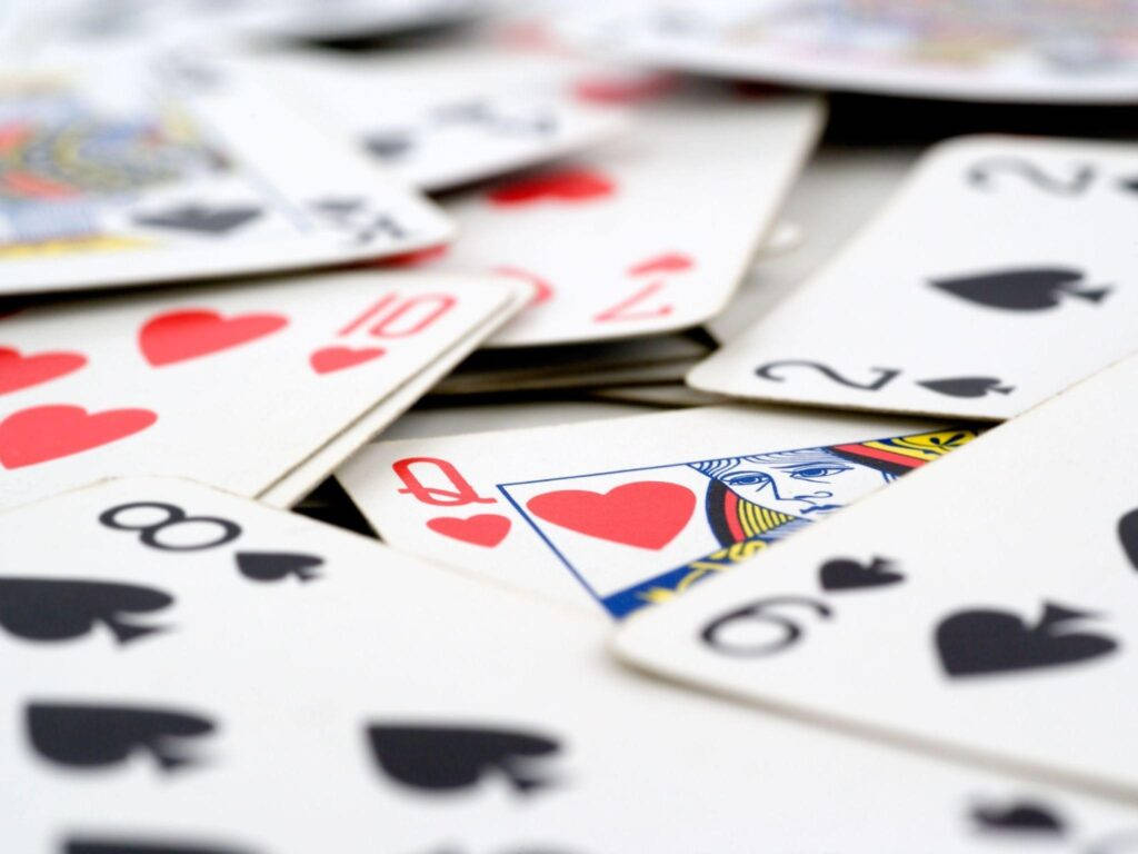 Casino 桌布 壁紙 — 淺景深特寫散落的撲克牌，聚焦於紅心及黑桃。