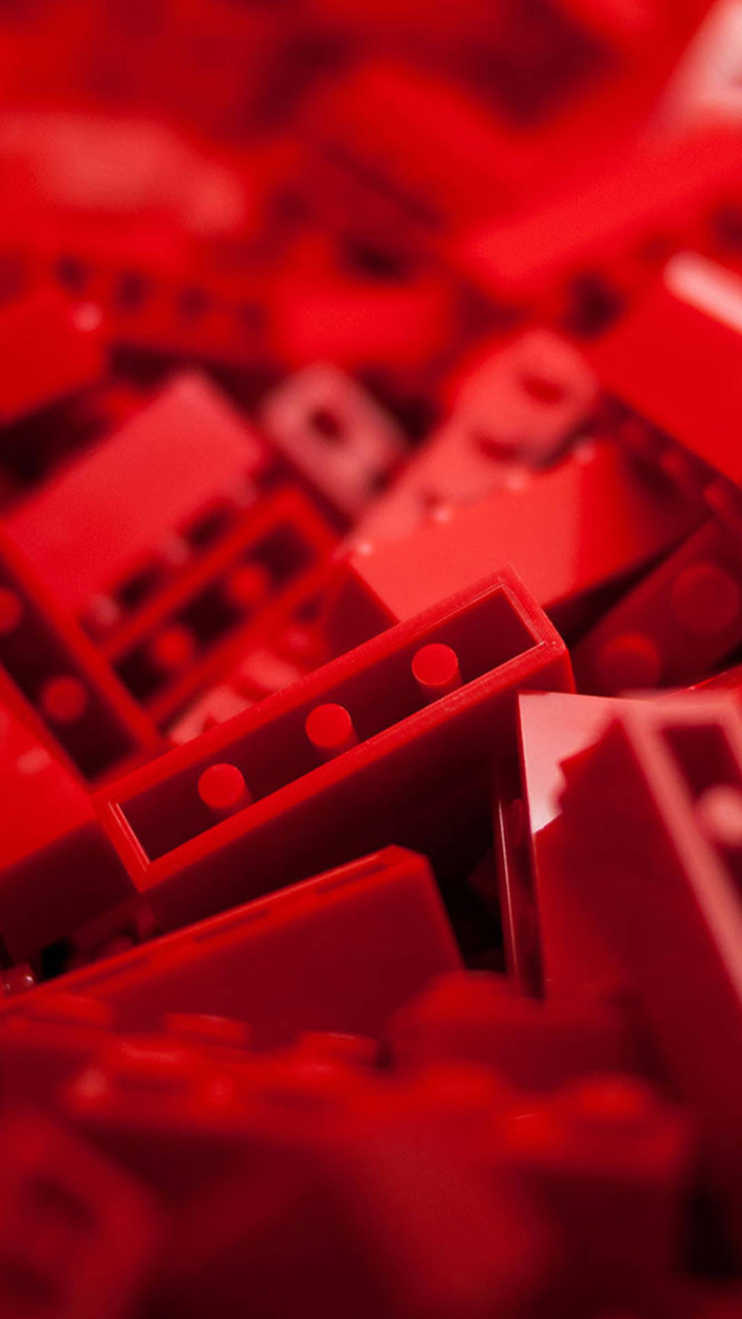 紅色 iPhone 桌布 壁紙 — 淺景深特寫散落的紅色LEGO積木，其中一塊對焦清晰。