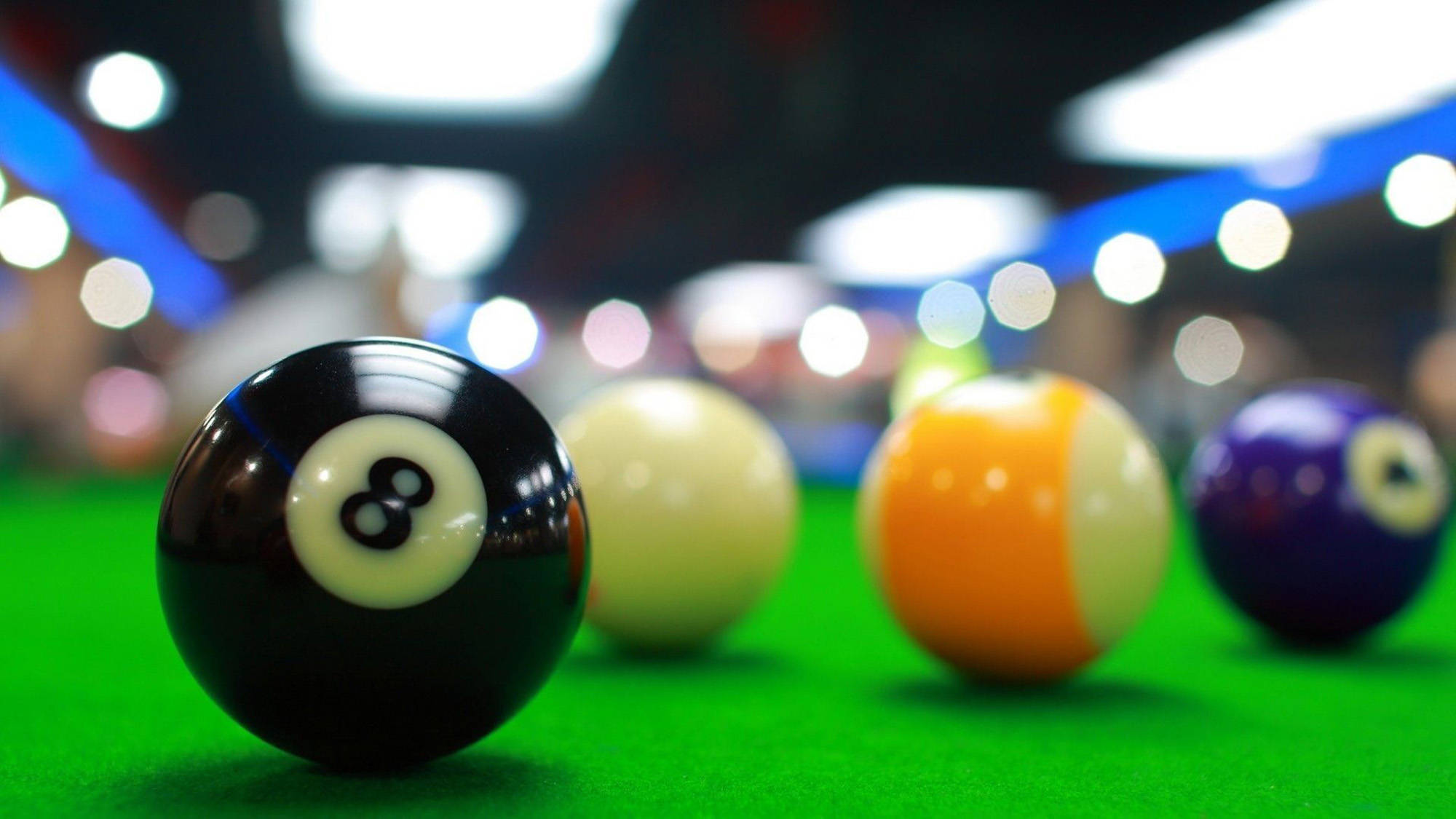 Snooker 桌布 壁紙 — 淺景深突顯綠色撞球桌上的一個黑色8號球，其他彩色球在背景中模糊。