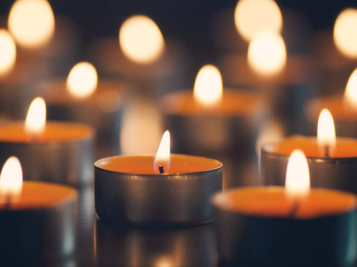 Condolence 桌布 壁紙 — 淺景深聚焦於黑暗中眾多柔和發光蠟燭中的一支閃爍茶燭。