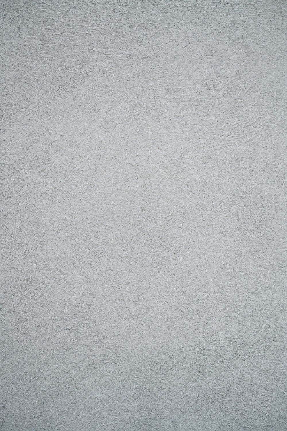 Solid Grey 桌布 壁紙 — 淺灰色平滑紋理牆面特寫，帶有細微凹凸和柔和陰影。