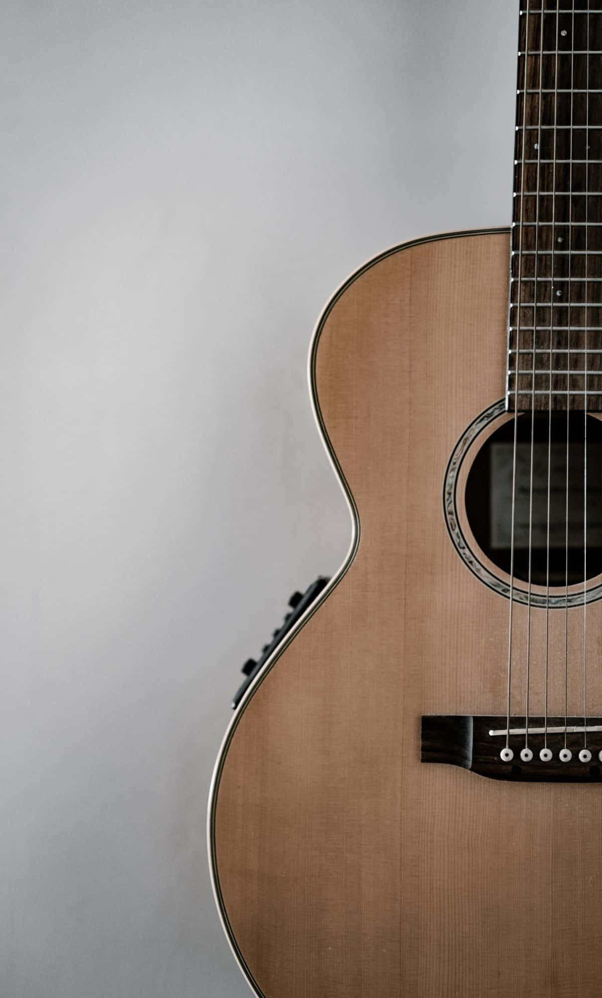 Guitar Aesthetic 桌布 壁紙 — 淺色木吉他特寫，帶銀色飾邊，背景為柔和灰色。