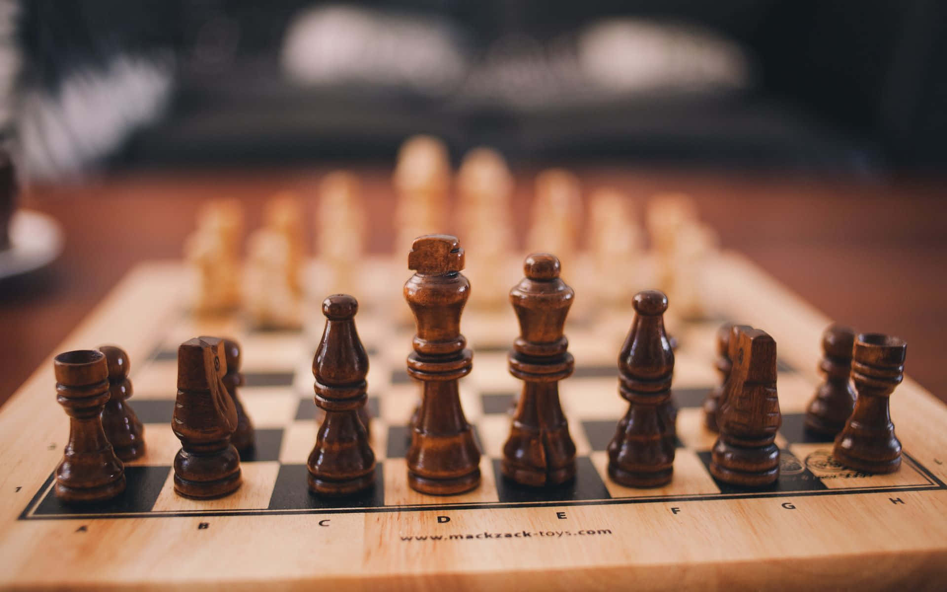 西洋棋 桌布 壁紙 — 淺色木板上深色木製西洋棋棋子的特寫，背景模糊。