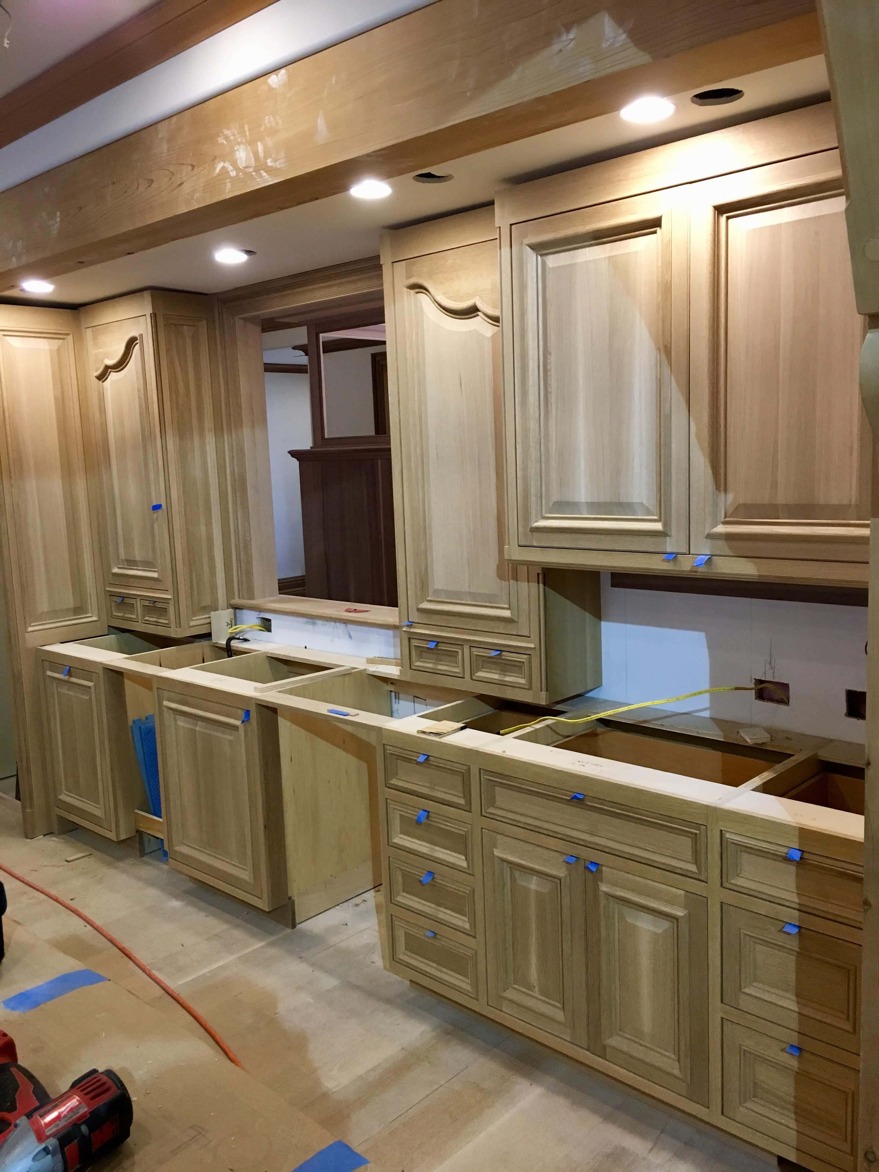 Cabinets 桌布 壁紙 — 淺色木質廚房櫥櫃正在施工中，檯面外露並帶有藍色遮蔽膠帶。