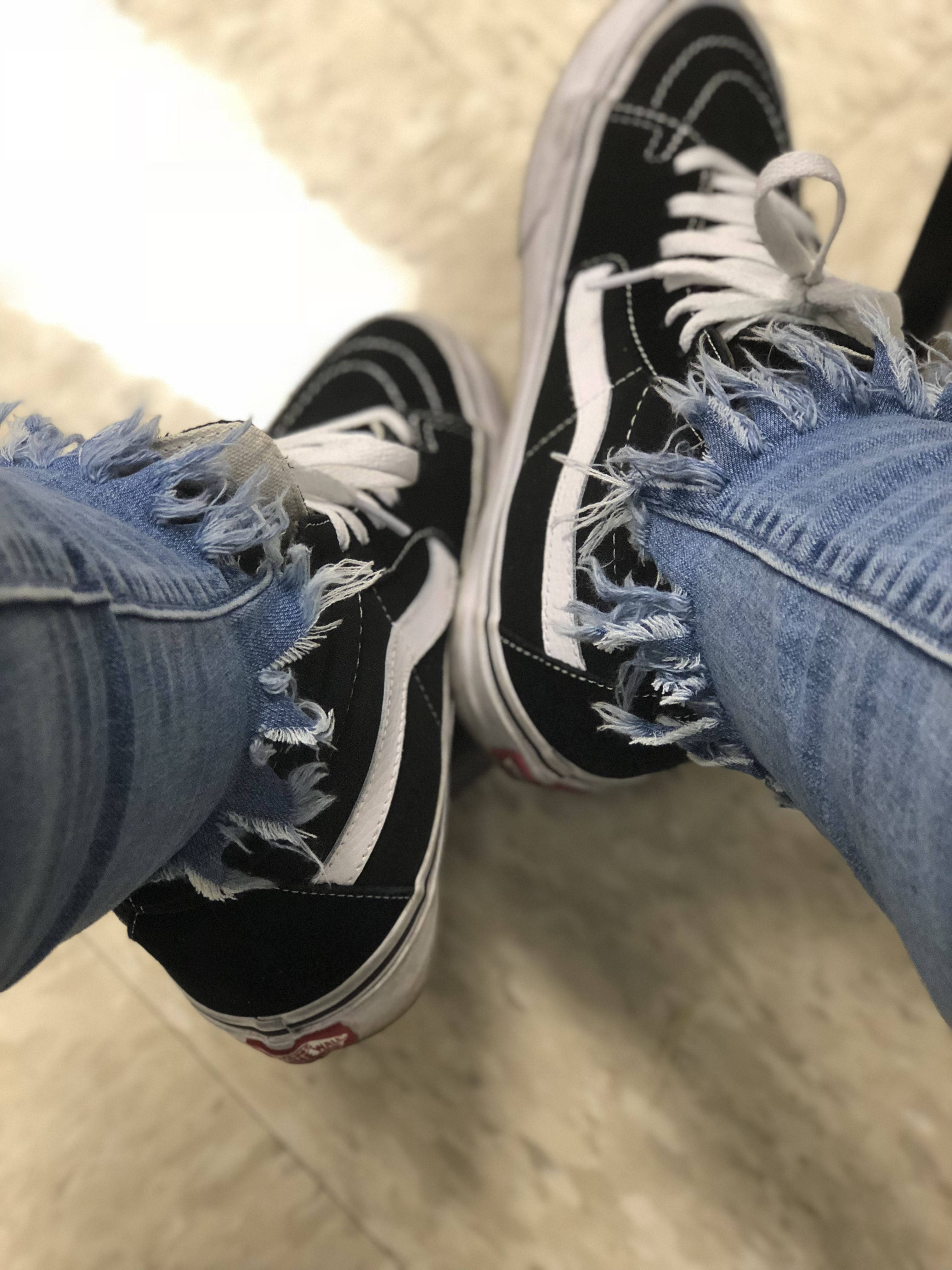 Vans Off The Wall 桌布 壁紙 — 淺色瓷磚地板上磨損的黑色Vans運動鞋與磨邊牛仔褲的特寫。