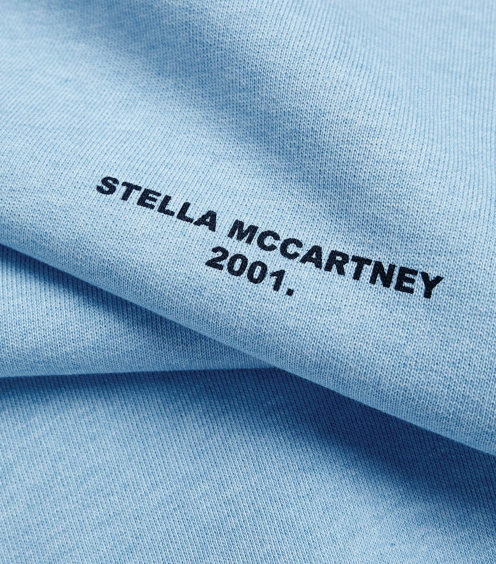 Designer Logo 桌布 壁紙 — 淺藍色布料特寫，黑色刺繡文字寫著「STELLA MCCARTNEY 2001」。
