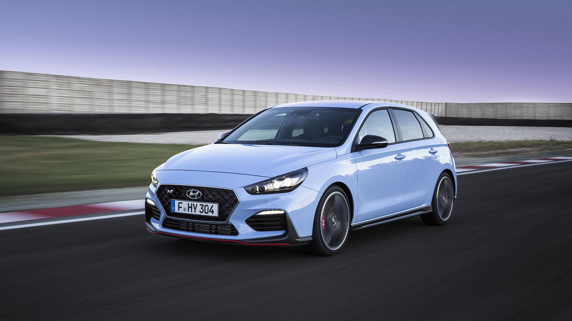 Hyundai 桌布 壁紙 — 淺藍色現代 i30 N 在賽道上疾馳，帶有模糊動感和紫色暮色天空。