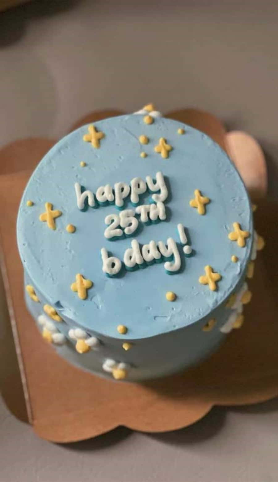 Happy Birthday Cake 桌布 壁紙 — 淺藍色糖霜生日蛋糕，白色糖霜寫著 happy 25th bday，周圍有黃色星星和圓點裝飾。