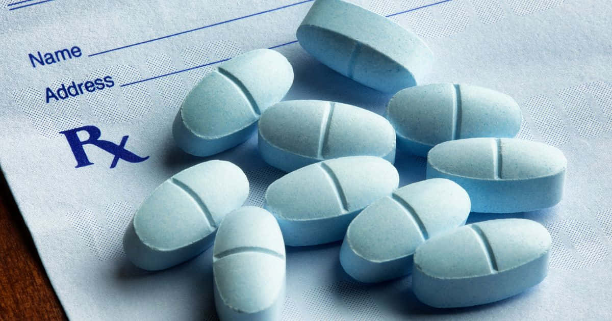 pills 桌布 壁紙 — 淺藍色藥丸散落在帶有Rx符號及姓名地址欄的處方箋上。
