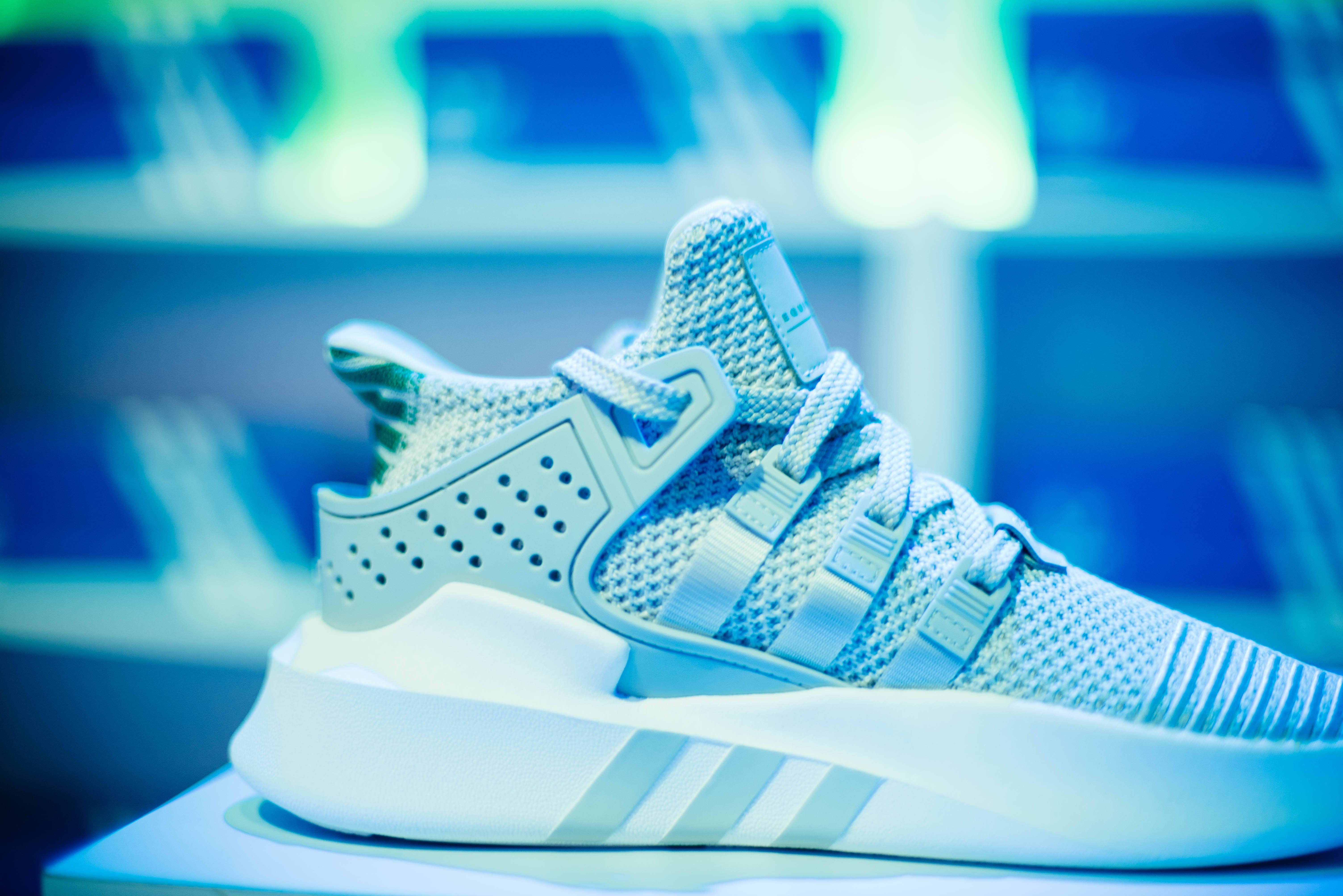 Sneaker 桌布 壁紙 — 淺藍色針織運動鞋的特寫，帶有白色條紋和穿孔細節，在冷藍色燈光下閃耀。