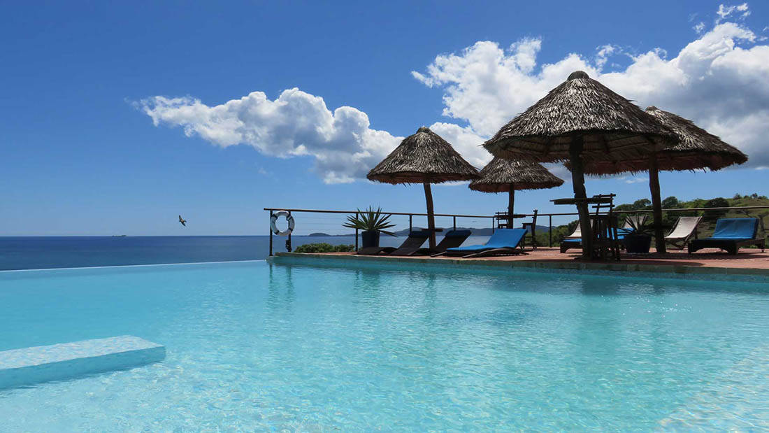 Resort 桌布 壁紙 — 清澈無邊際泳池與碧藍海洋融為一體，上方是藍天白雲。
