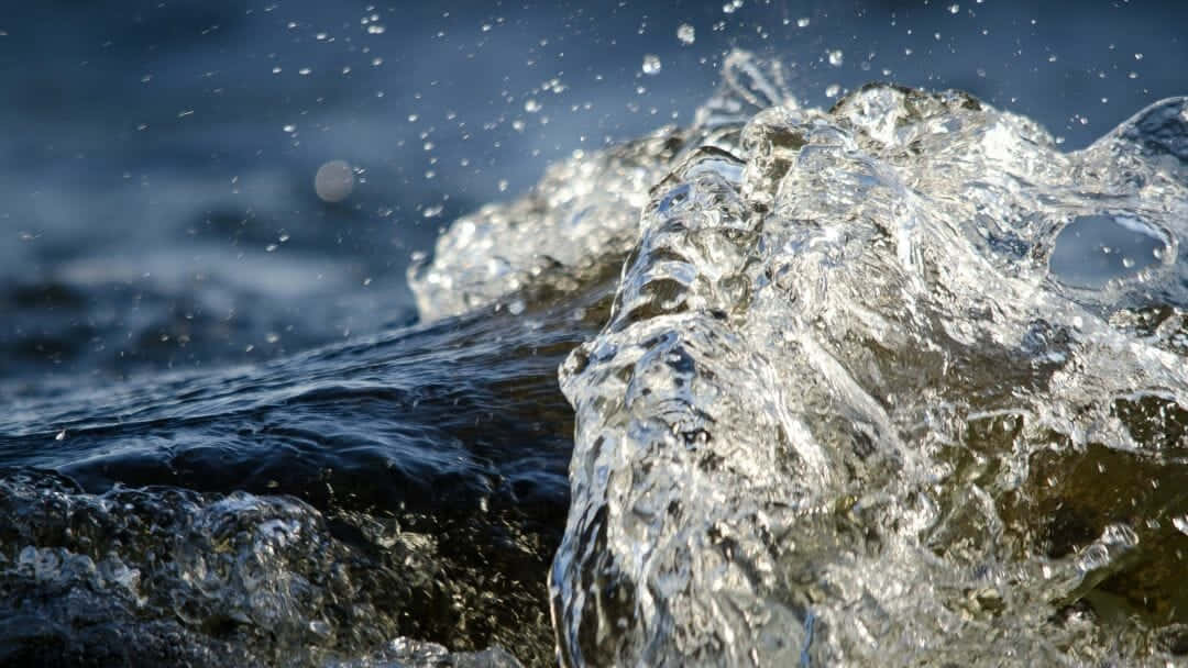 桌布 壁紙 — 清澈的水在深藍色背景上撞擊和飛濺，水滴在運動中凝固。