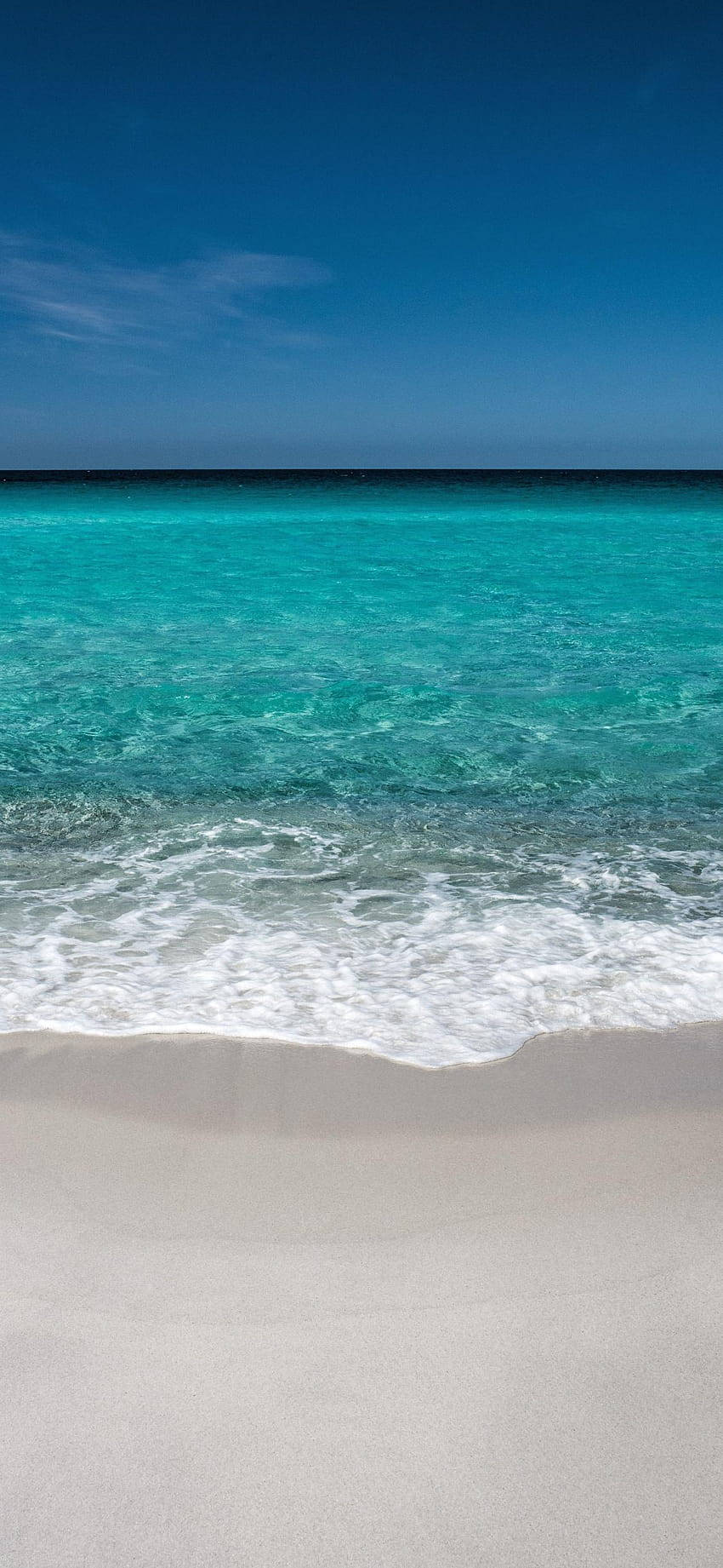 iPhone X Beach 桌布 壁紙 — 清澈的碧綠海浪輕輕拍打著純淨的白色沙灘，上方是廣闊的深藍色天空。