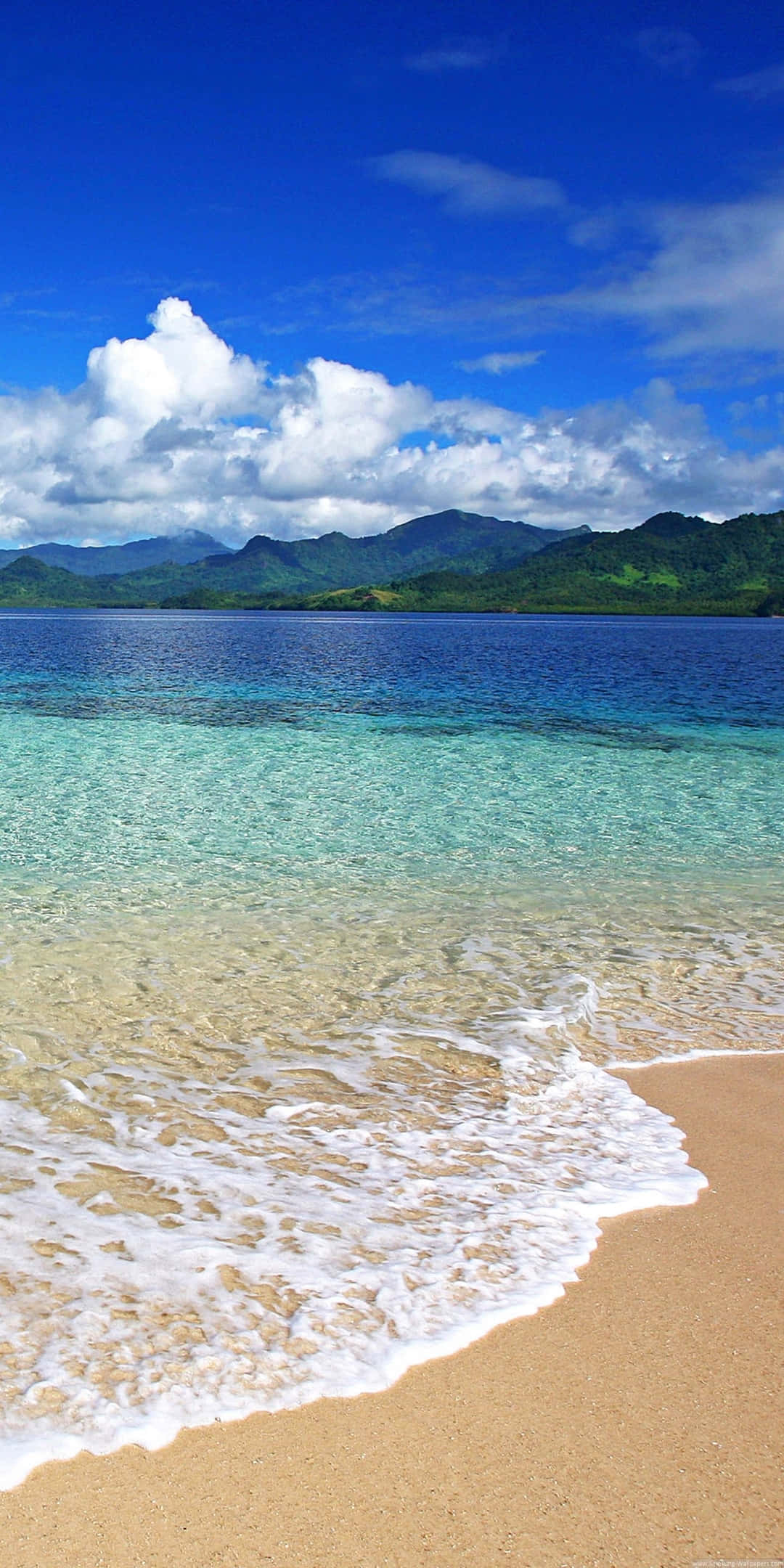 Pixel 3 Beach 桌布 壁紙 — 清澈的碧綠海浪輕輕拍打著金色的沙灘，上方是湛藍的天空和蓬鬆的白雲。