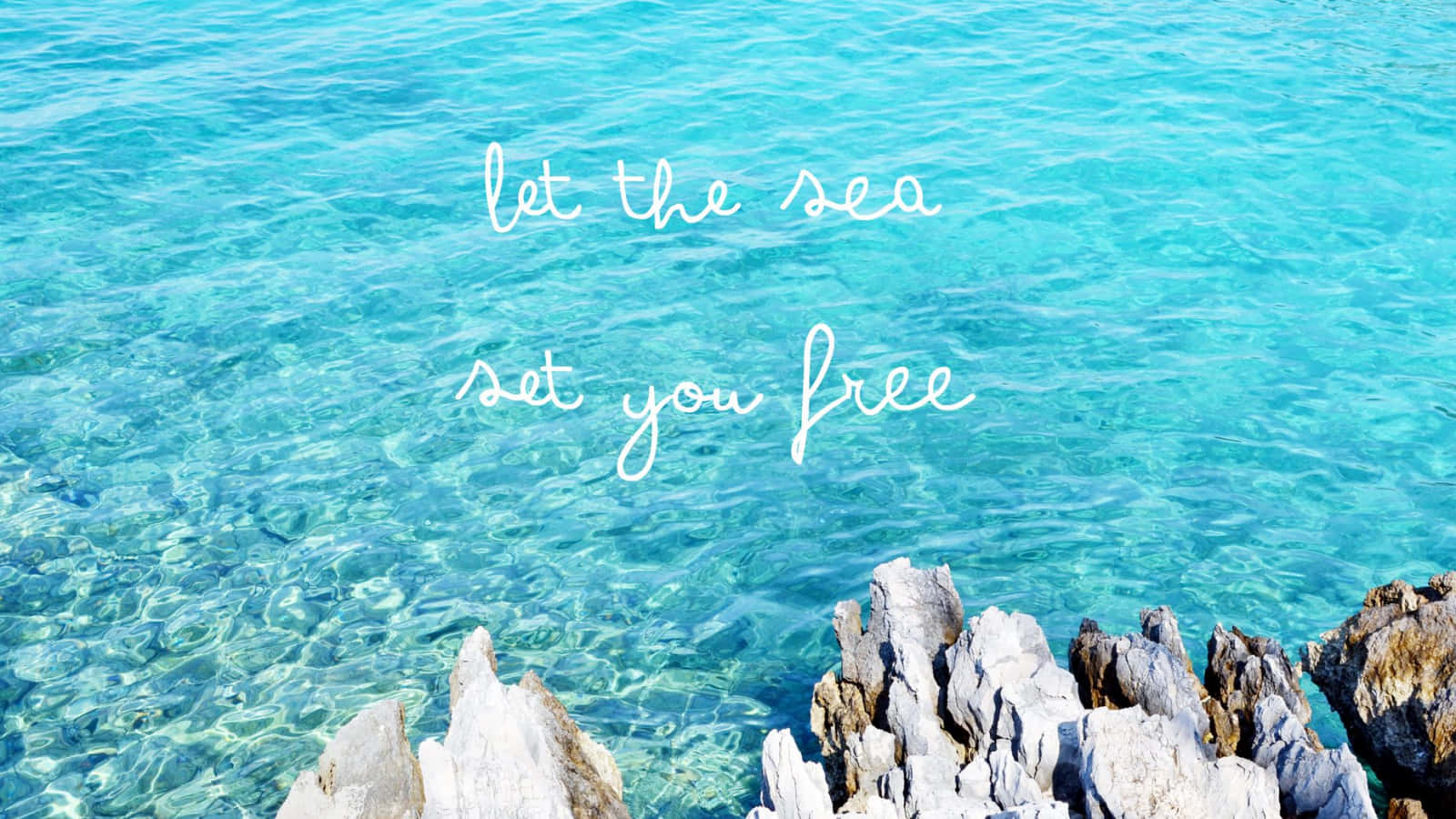 Sea 桌布 壁紙 — 清澈碧綠的海水拍打著參差不齊的白色岩石，上面有草書文字寫著讓大海釋放你。