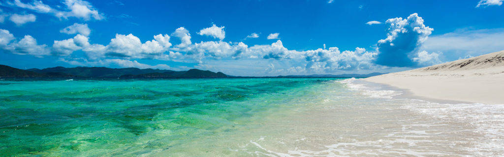 high 桌布 壁紙 — 清澈碧綠的海水輕拍著純淨的白色沙灘，上方是湛藍的天空和蓬鬆的白雲。