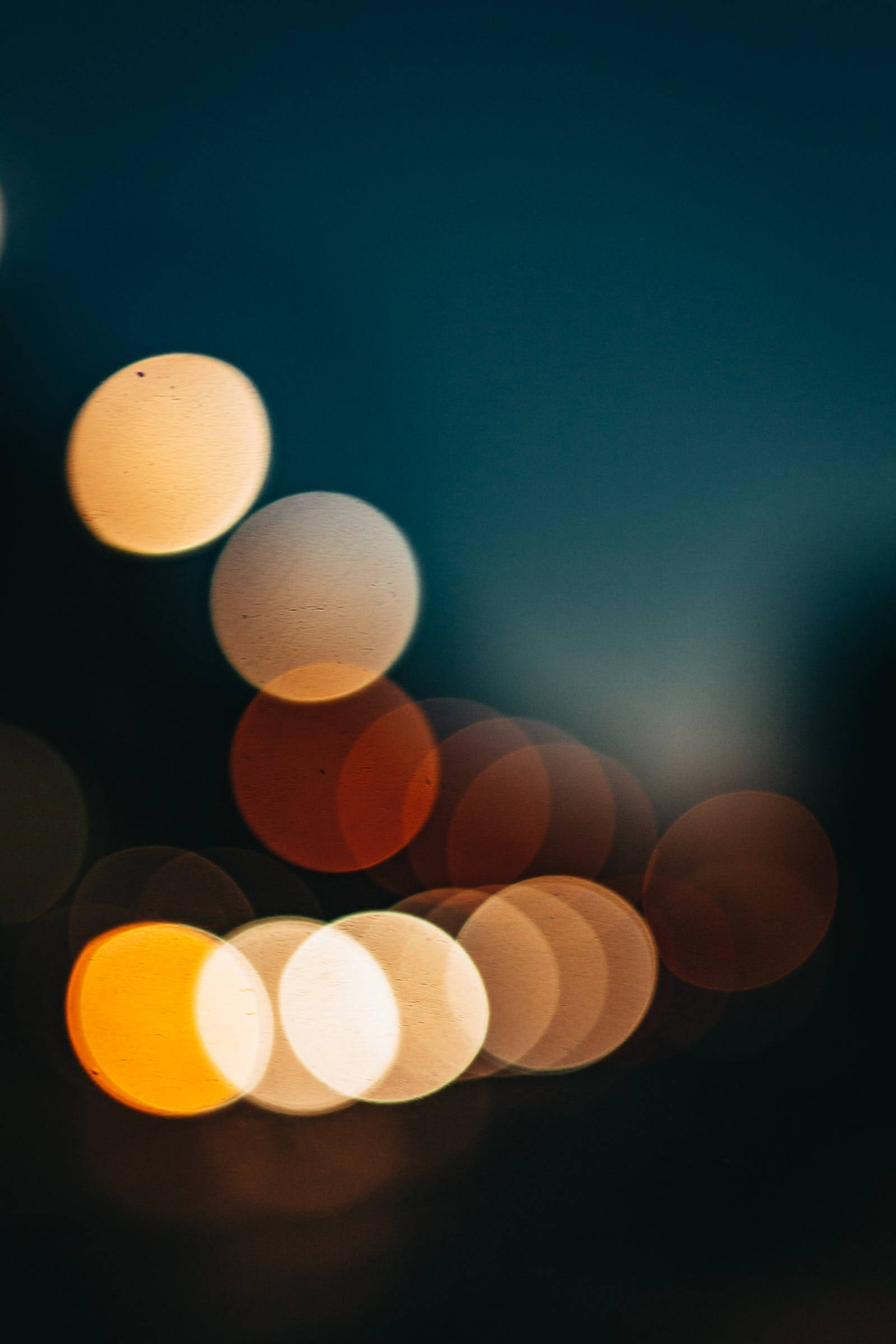 Bokeh 桌布 壁紙 — 溫暖光線的柔和發光球體在深藍綠色夜空中漂浮，營造出夢幻般的散景效果。