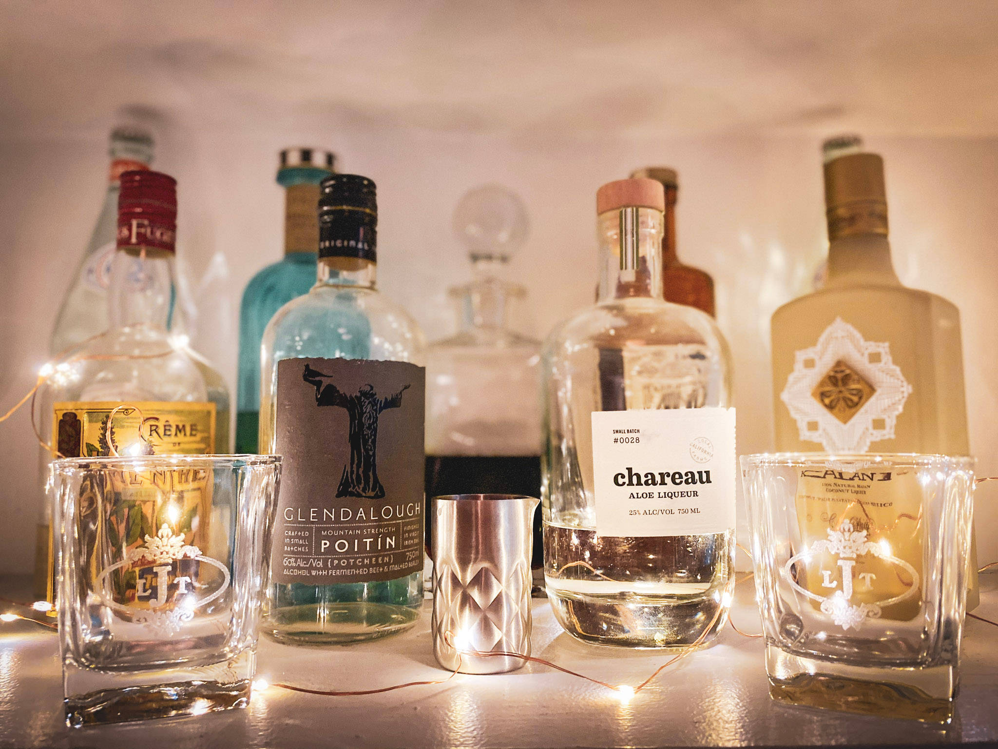 drinks 桌布 壁紙 — 溫暖照亮的工藝烈酒瓶和裝飾著仙女燈的玻璃杯，營造出親密的酒吧場景。