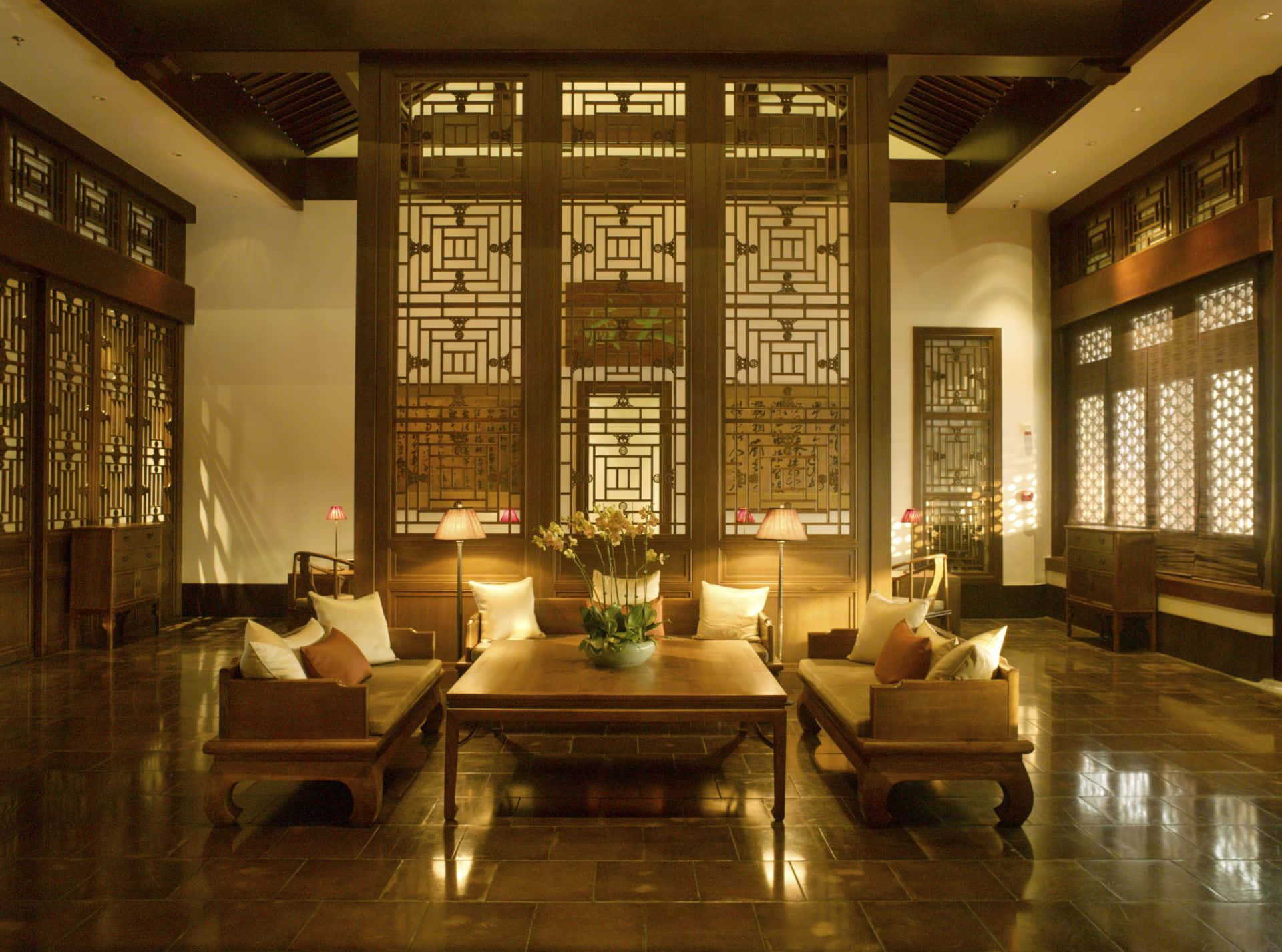 Interior Design 桌布 壁紙 — 溫暖照明的傳統木製休息室，配有精緻的格子屏風和圍繞中央桌子擺放的低矮座椅。