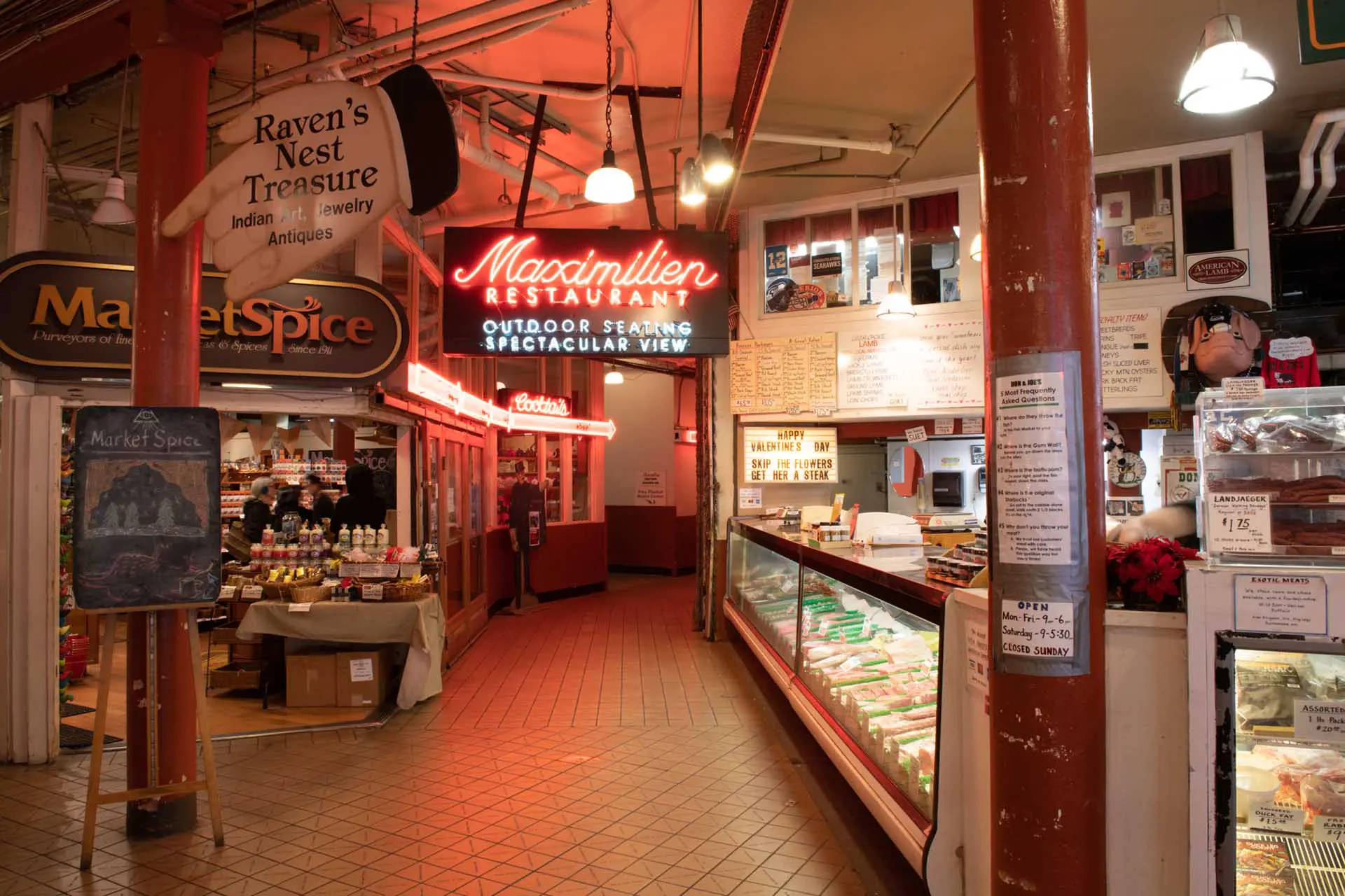 Pike Place Market 桌布 壁紙 — 溫暖照明的室內市場走廊，瓷磚地板上設有餐廳和商店的霓虹燈標誌。