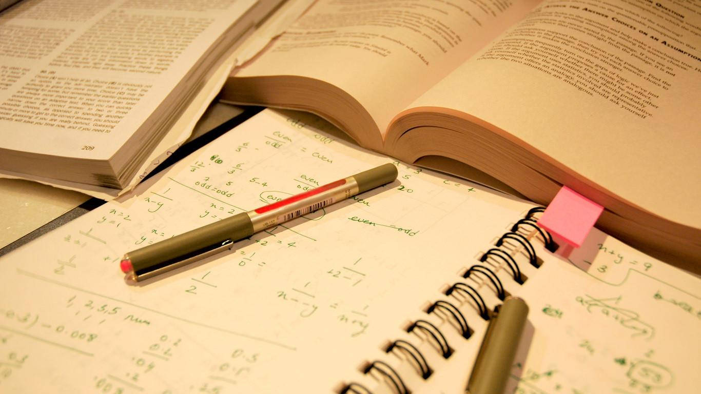 書桌上打開的教科書和筆記本，上面有數學方程式和筆。