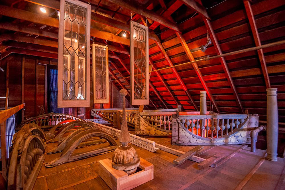 Mansion 桌布 壁紙 — 溫暖照明的閣樓空間，在裸露橫樑下展示復古木製船隻零件和懸掛的鉛玻璃窗。