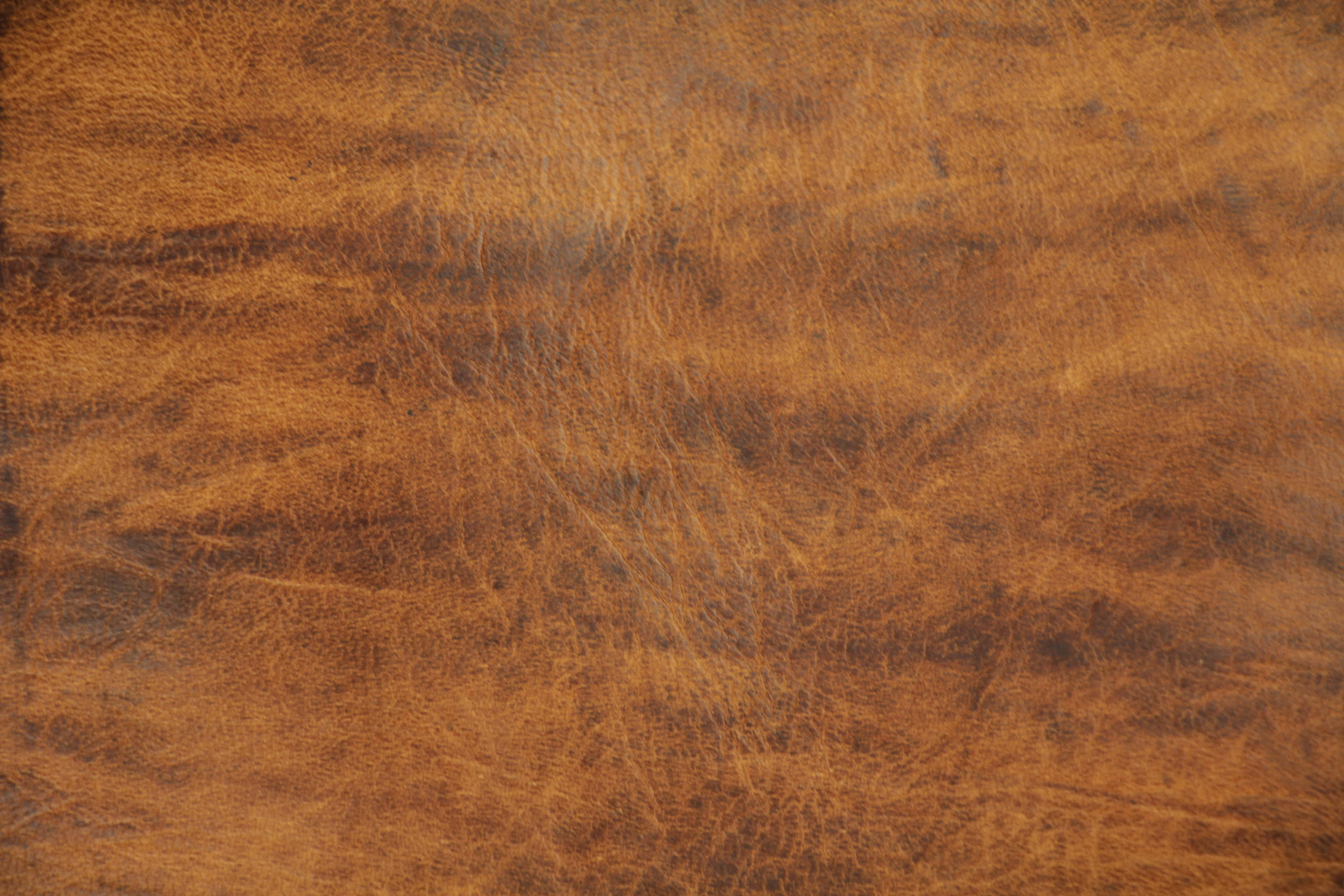 texture 桌布 壁紙 — 溫暖燈光下，天然紋理和細微皺褶的濃郁棕色皮革特寫。