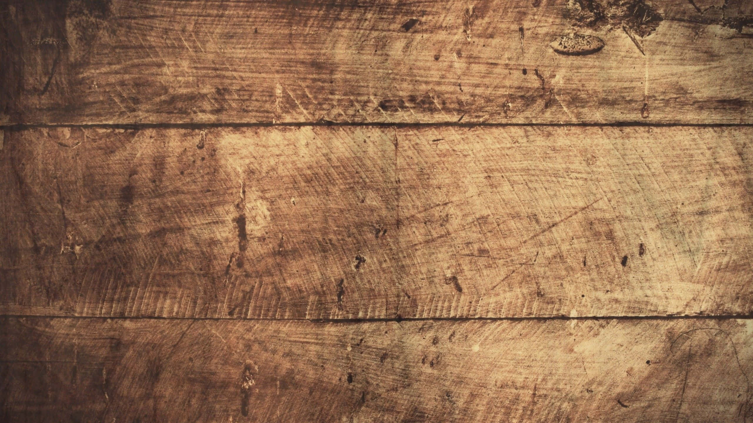 Wood Grain 桌布 壁紙 — 溫暖燈光下風化木板的特寫，帶有深木紋刮痕和天然節疤。