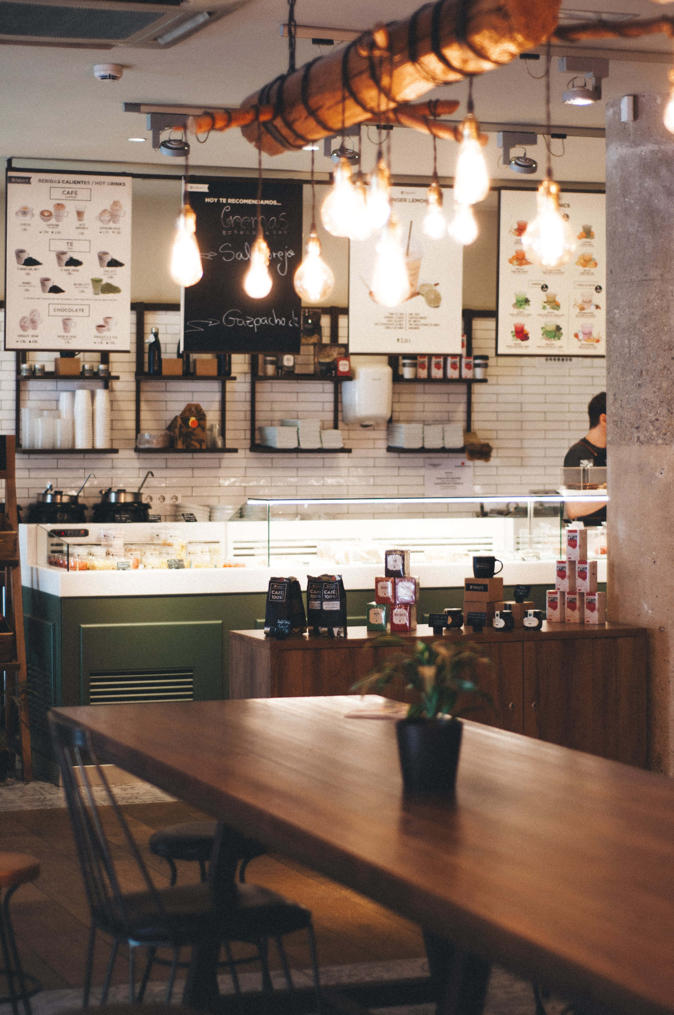 Restaurant 桌布 壁紙 — 溫暖燈光的咖啡館內部，有木桌、吊燈和瓷磚牆上的菜單板。