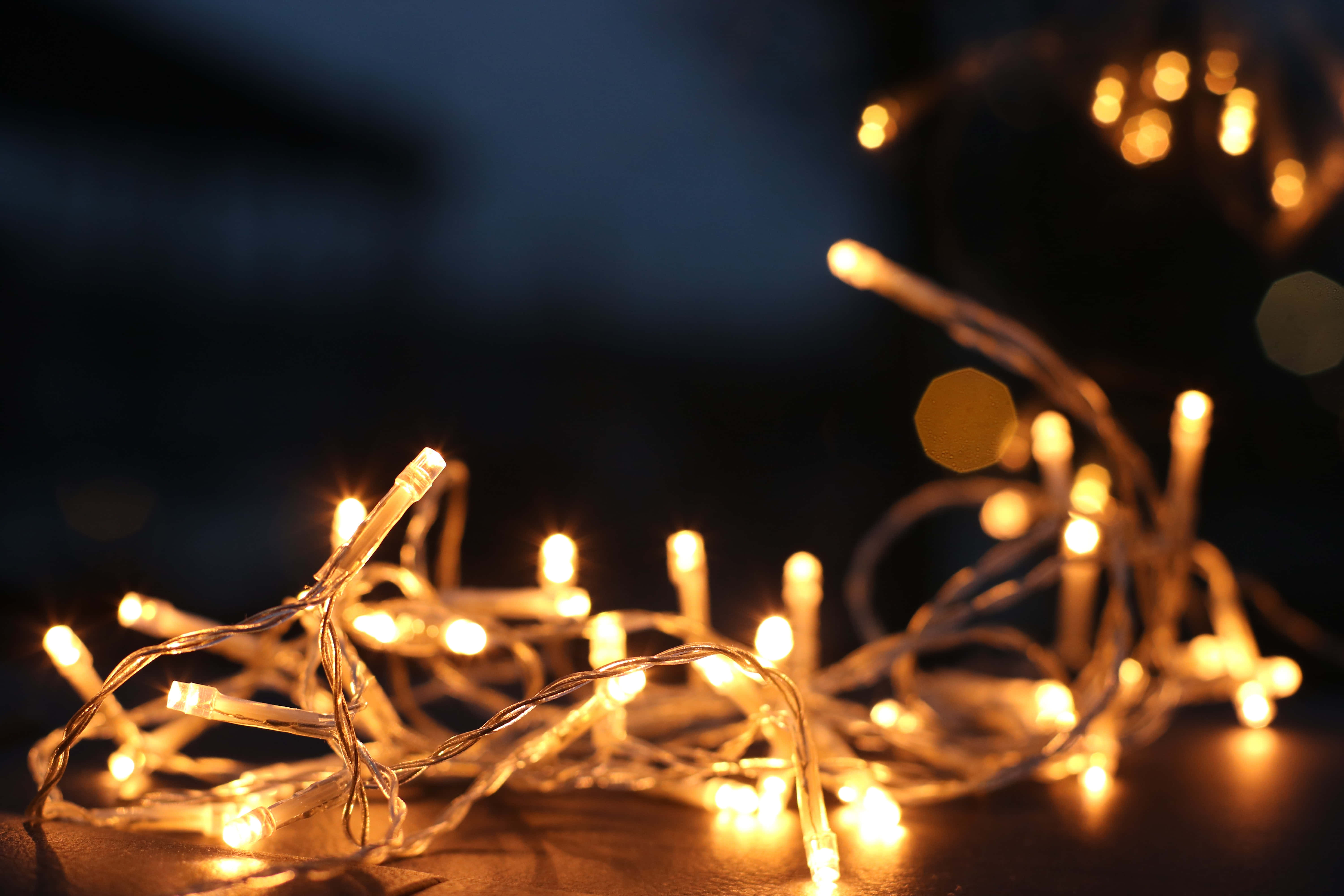 lights 桌布 壁紙 — 溫暖發光的仙女燈在黑暗模糊的背景上柔和閃爍，營造出舒適的節日氛圍。