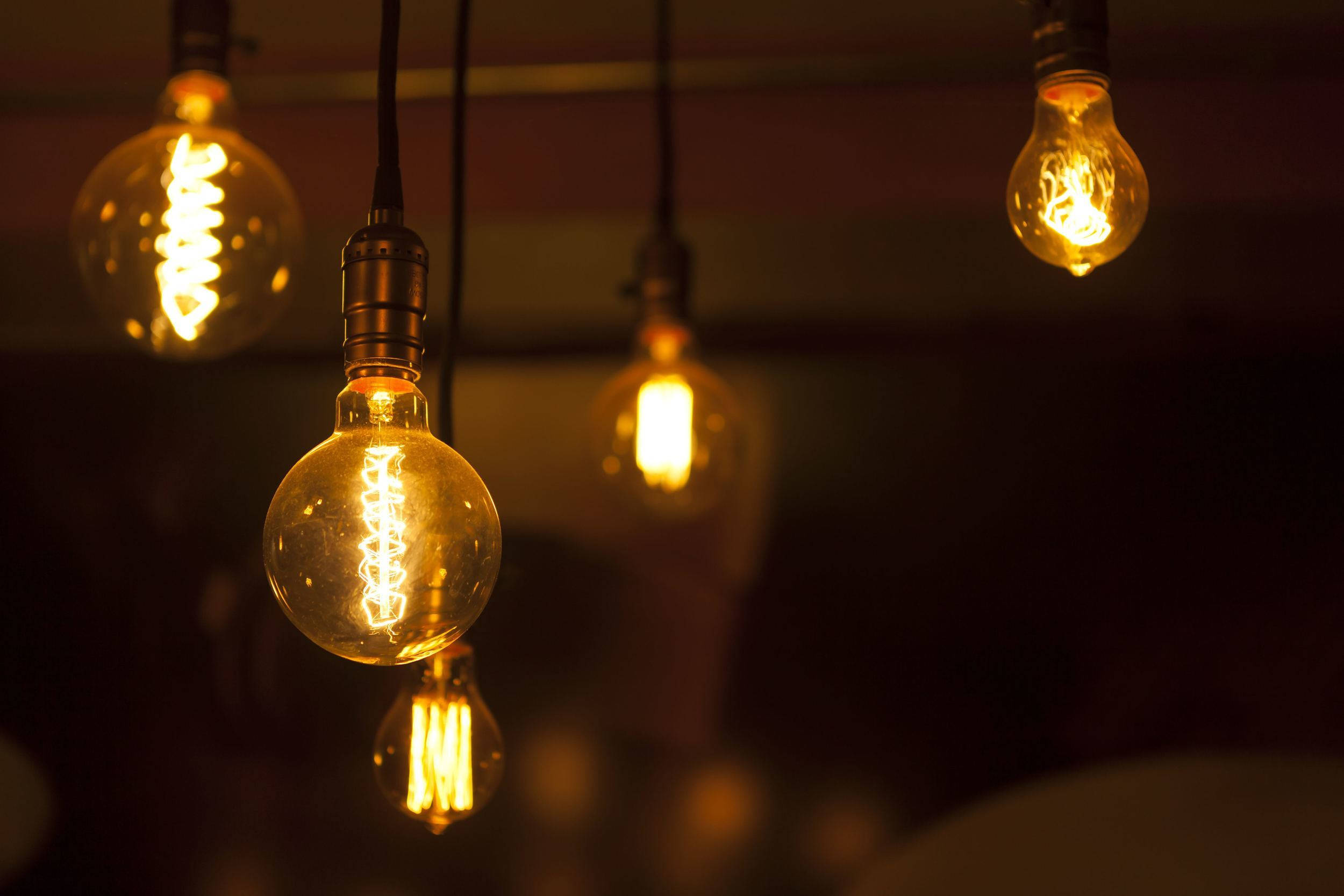 Light 桌布 壁紙 — 溫暖發光的復古燈絲燈泡懸掛在光線昏暗的舒適室內空間中。
