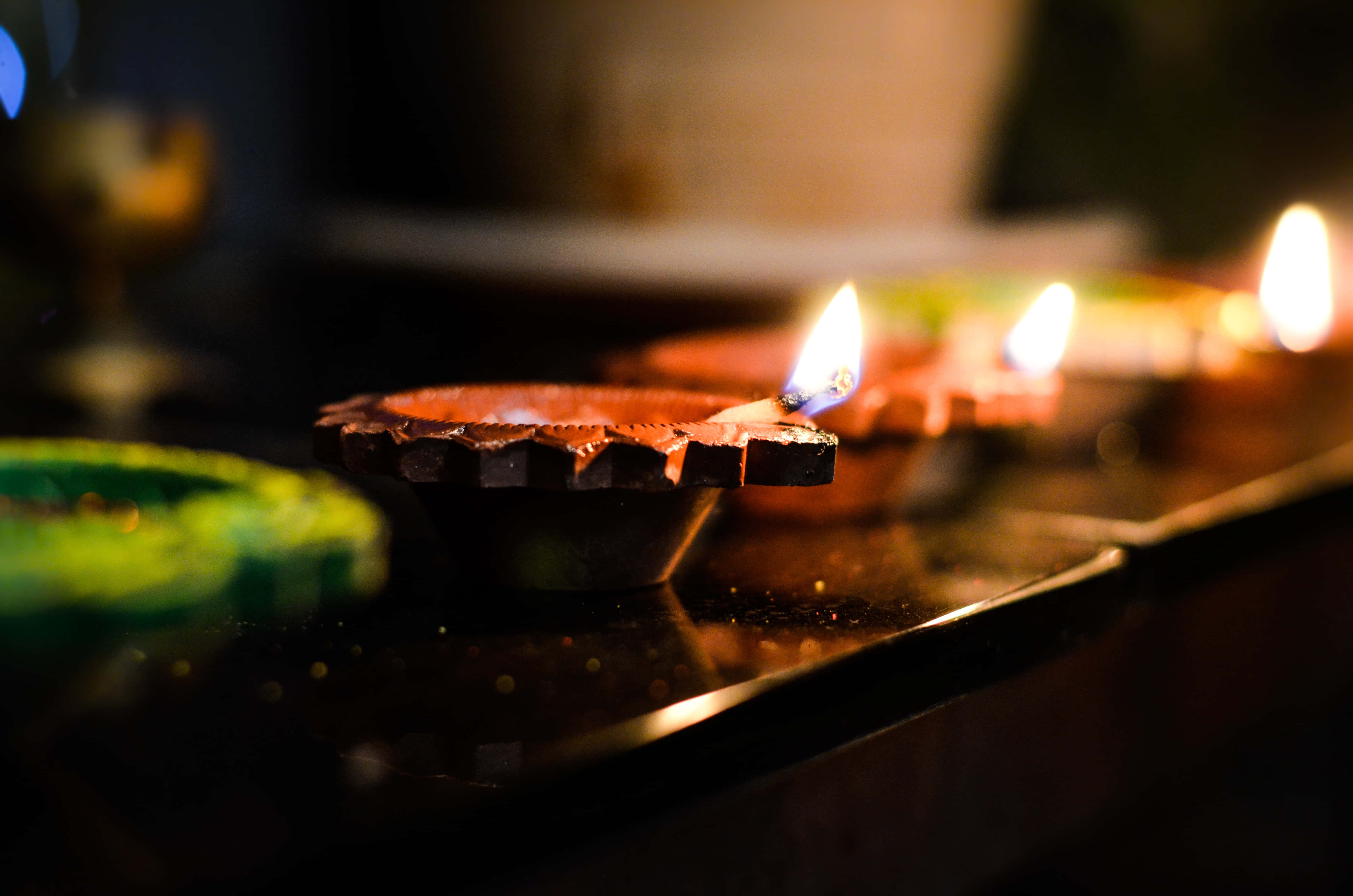 排燈節 桌布 壁紙 — 溫暖發光的油燈在寧靜的夜晚環境中，將柔和的光線投射在深色木質表面上。