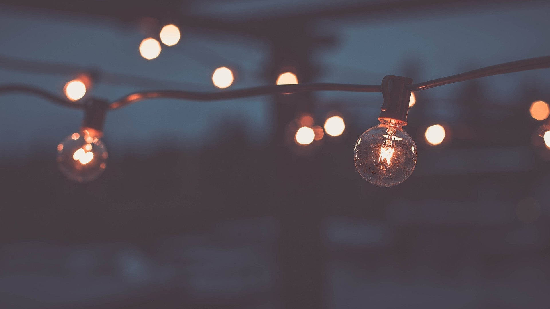 Fairy Lights Aesthetic 桌布 壁紙 — 溫暖發光的燈串輕輕懸掛在昏暗的暮色天空中，營造出舒適的環境光芒。