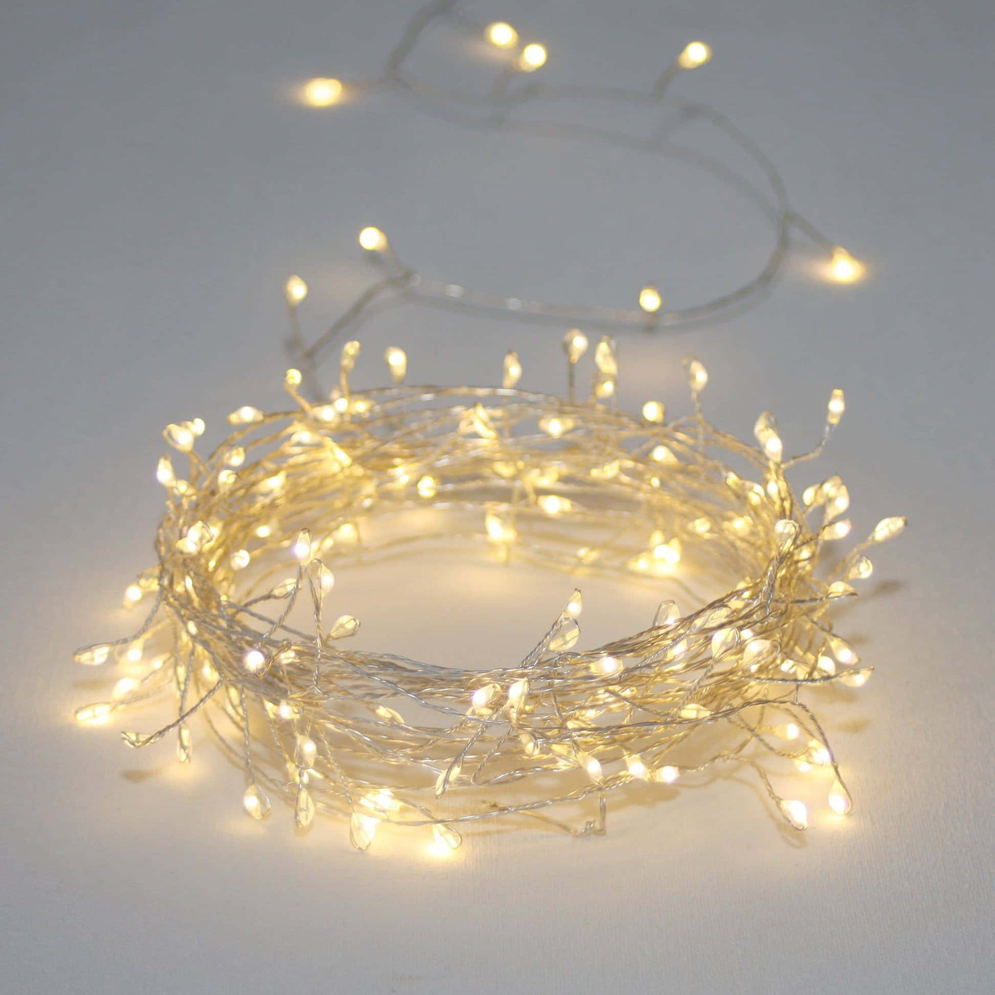 Led Light 桌布 壁紙 — 溫暖發光的童話燈串成線圈，在純白表面上投射出柔和的金色光芒。