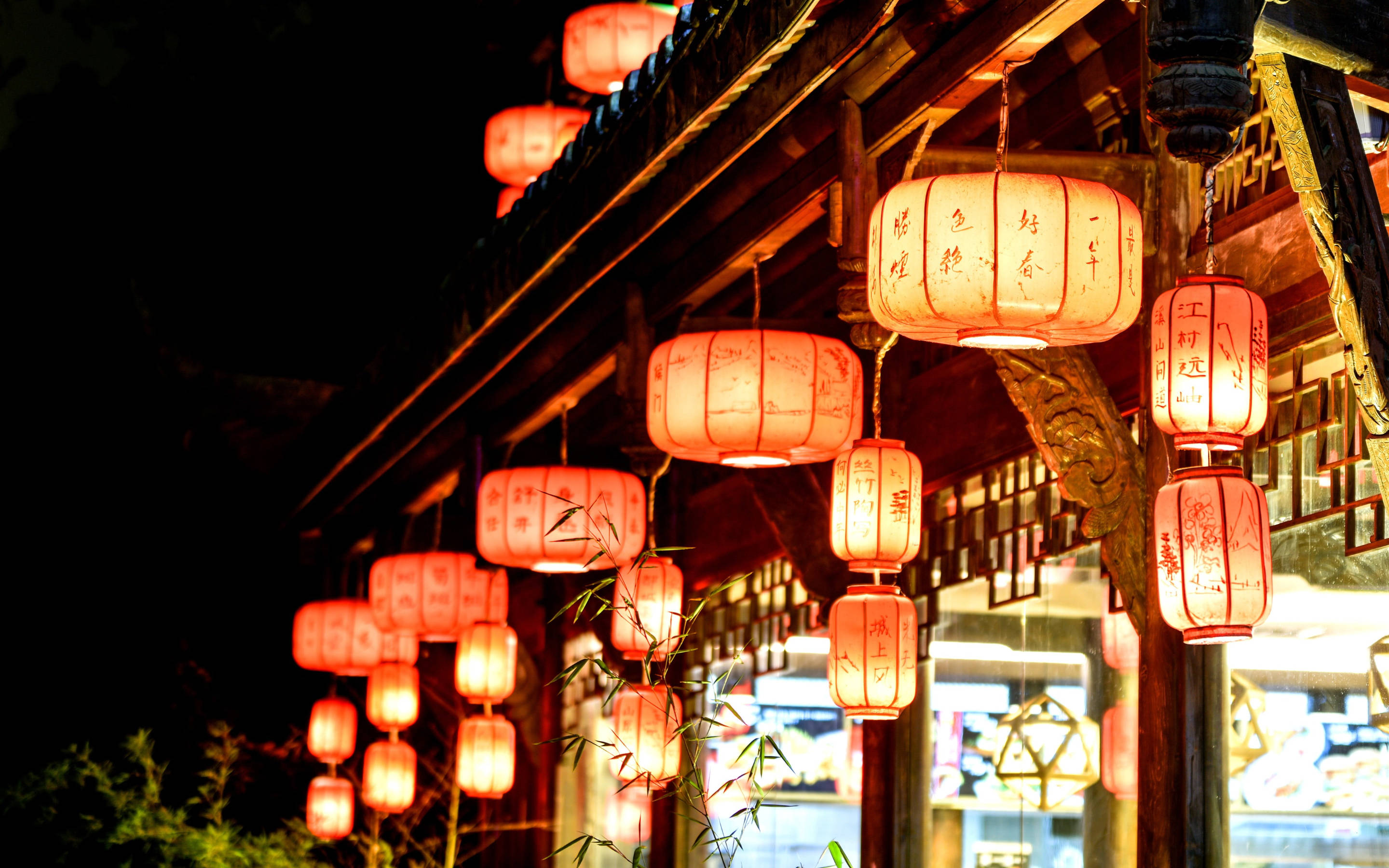 Chengdu 桌布 壁紙 — 溫暖發光的紅色燈籠掛在傳統木簷下，映襯著漆黑的夜空，在竹枝上投下柔和的光線。