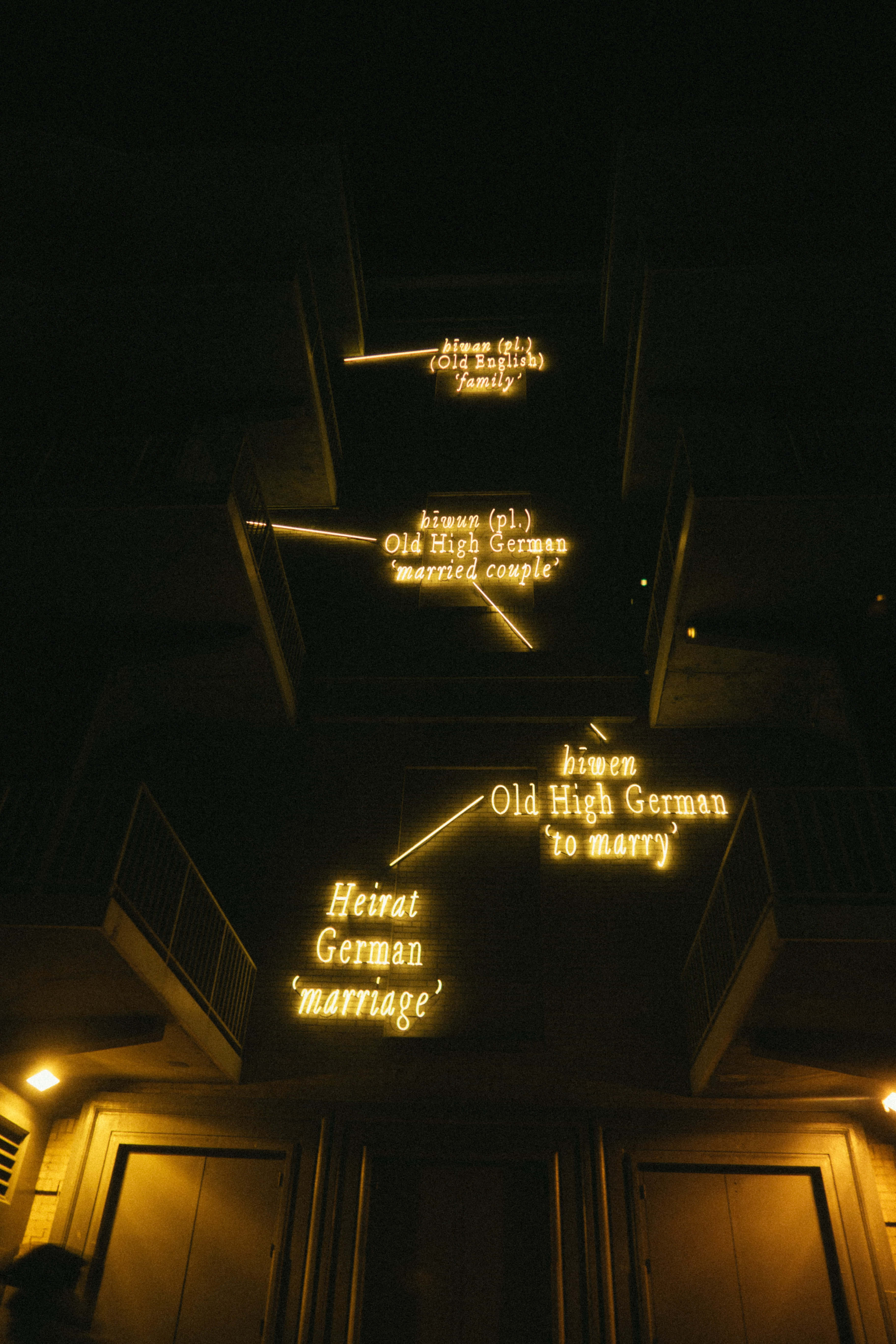 Aesthetic Grunge Neon Signs 桌布 壁紙 — 溫暖發光的霓虹燈牌在夜晚的黑暗建築物外牆上展示婚姻詞彙的詞源根源。