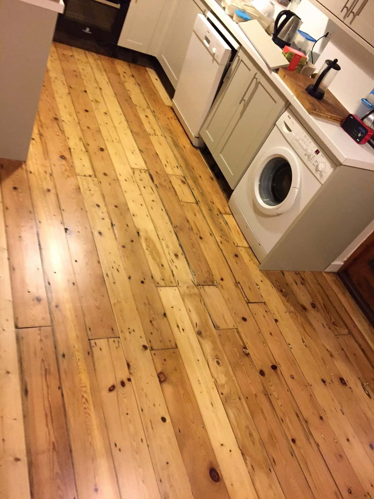 Wooden Floor 桌布 壁紙 — 溫暖的木地板穿過明亮的廚房，配有白色電器和櫥櫃。