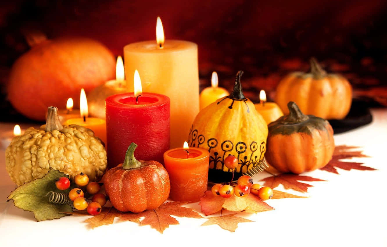 Halloween Candles 桌布 壁紙 — 溫暖的秋日靜物，發光的蠟燭、南瓜和楓葉排列在白色表面上。