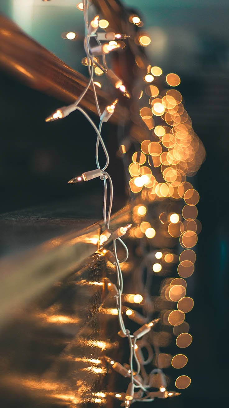 Christmas Lights Aesthetic 桌布 壁紙 — 溫暖的金色仙女燈在暮色中垂掛在深色木欄杆上，形成柔和的散景。